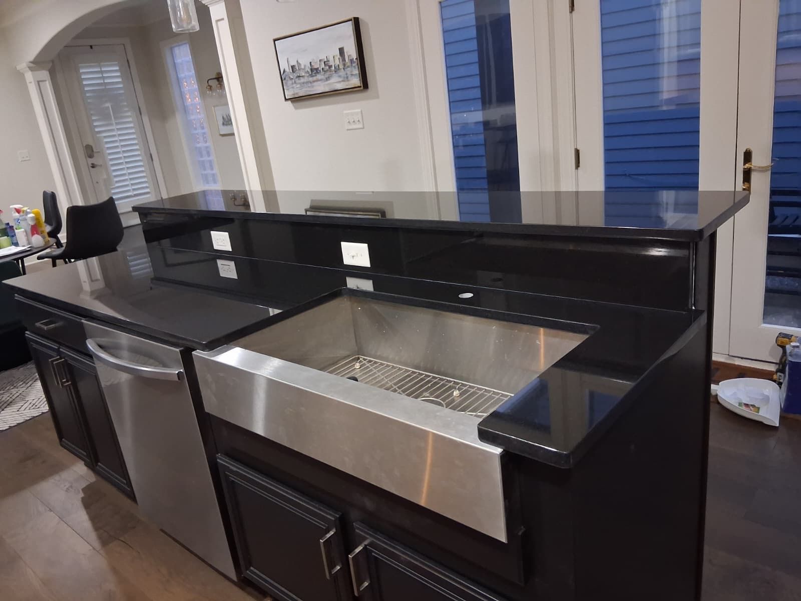 Black kitchen island with stainless sink and dishwasher in a bright room