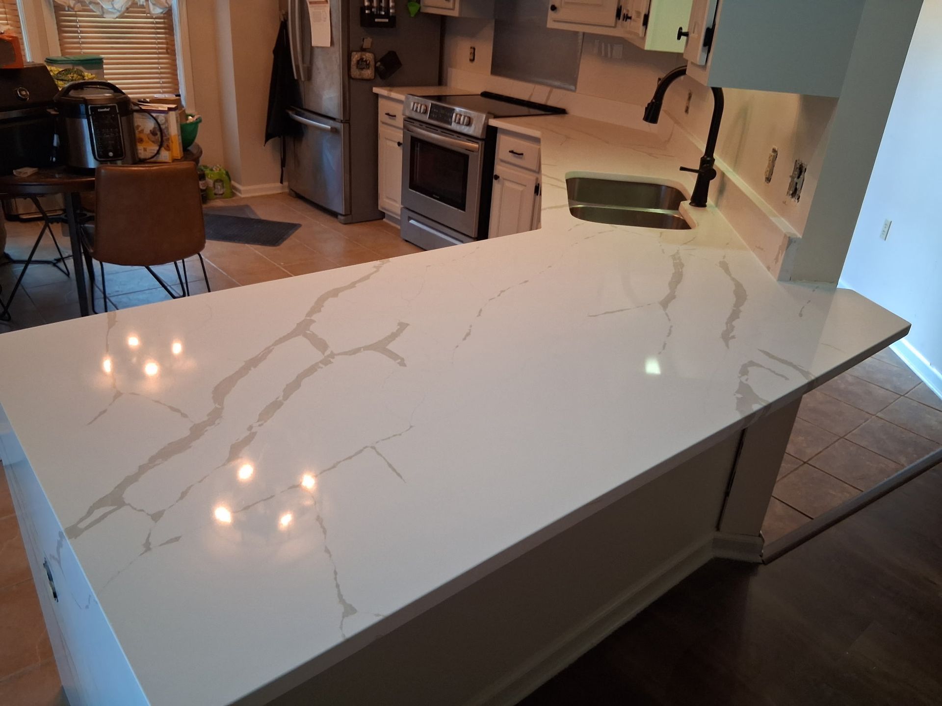 Modern kitchen with a large white marble-pattern island and stainless steel appliances