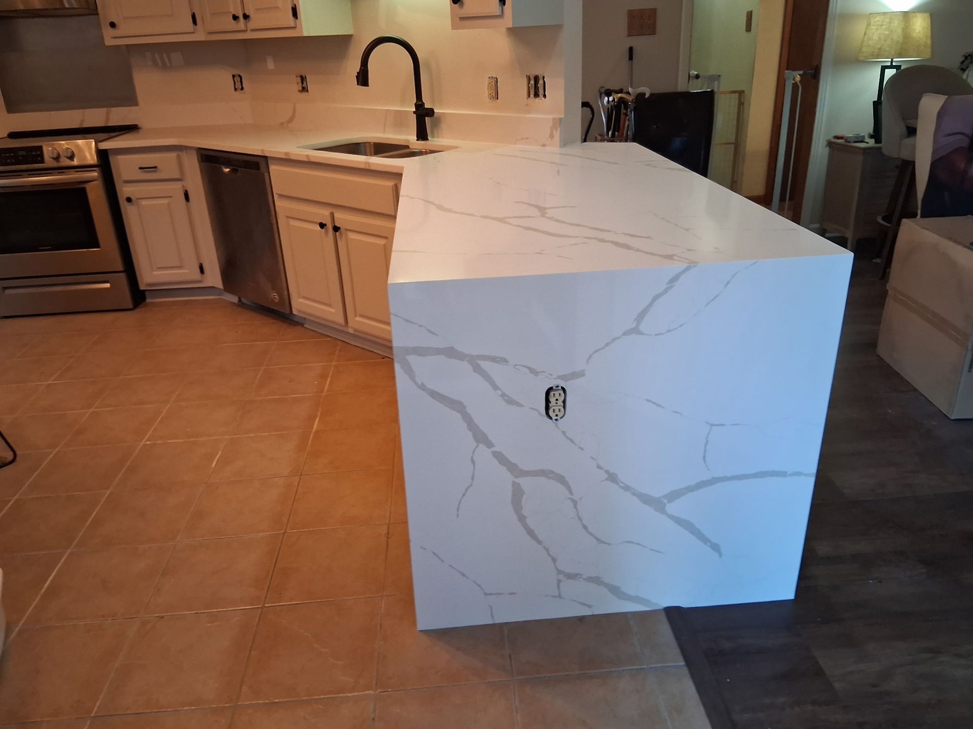 Kitchen with large white marble-pattern island and light wood cabinets, viewed from the side