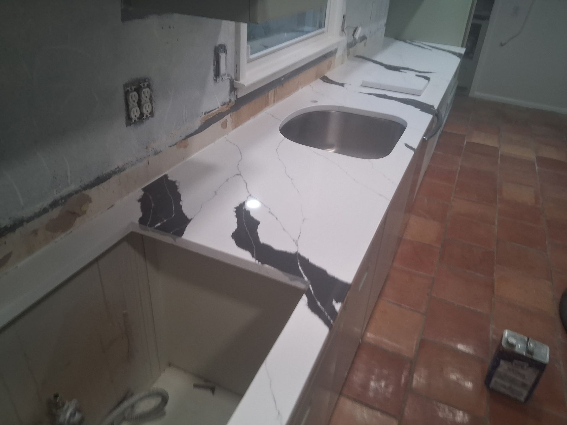 Damaged kitchen countertop with a large crack and broken sink area, debris on the floor.