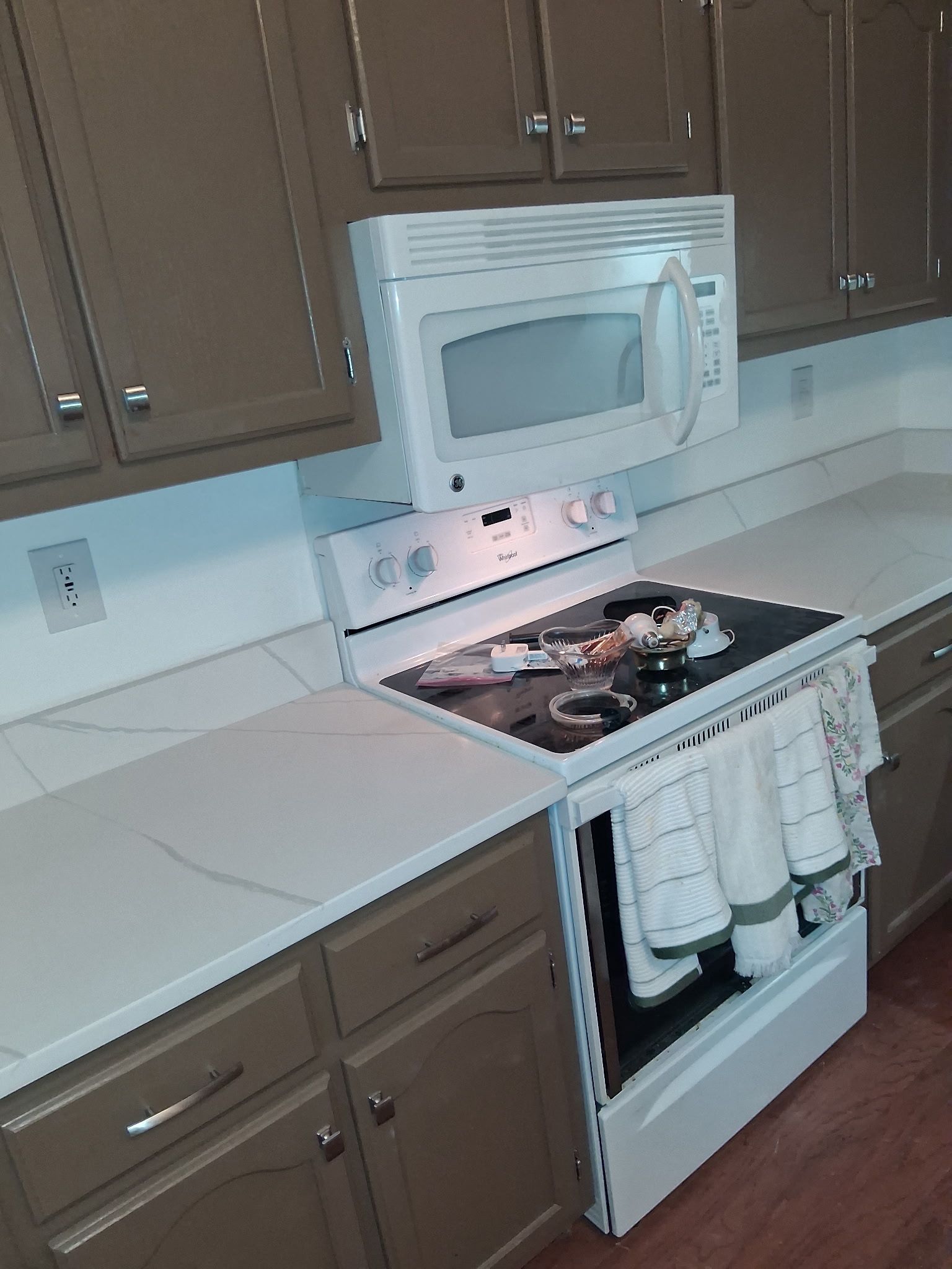 Kitchen with white appliances, brown cabinets, and a stove with towels hanging on the oven door