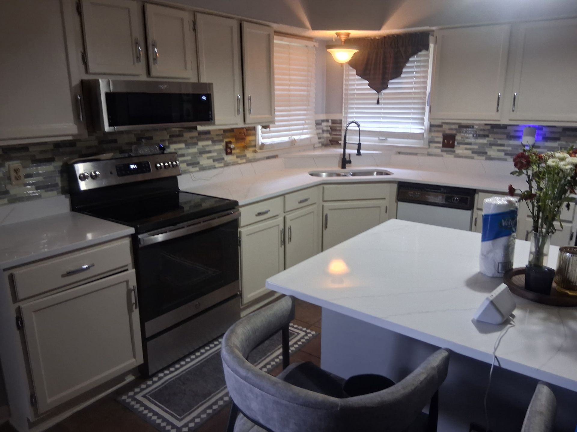 Modern kitchen with white cabinets, black appliances, island, and window over the sink