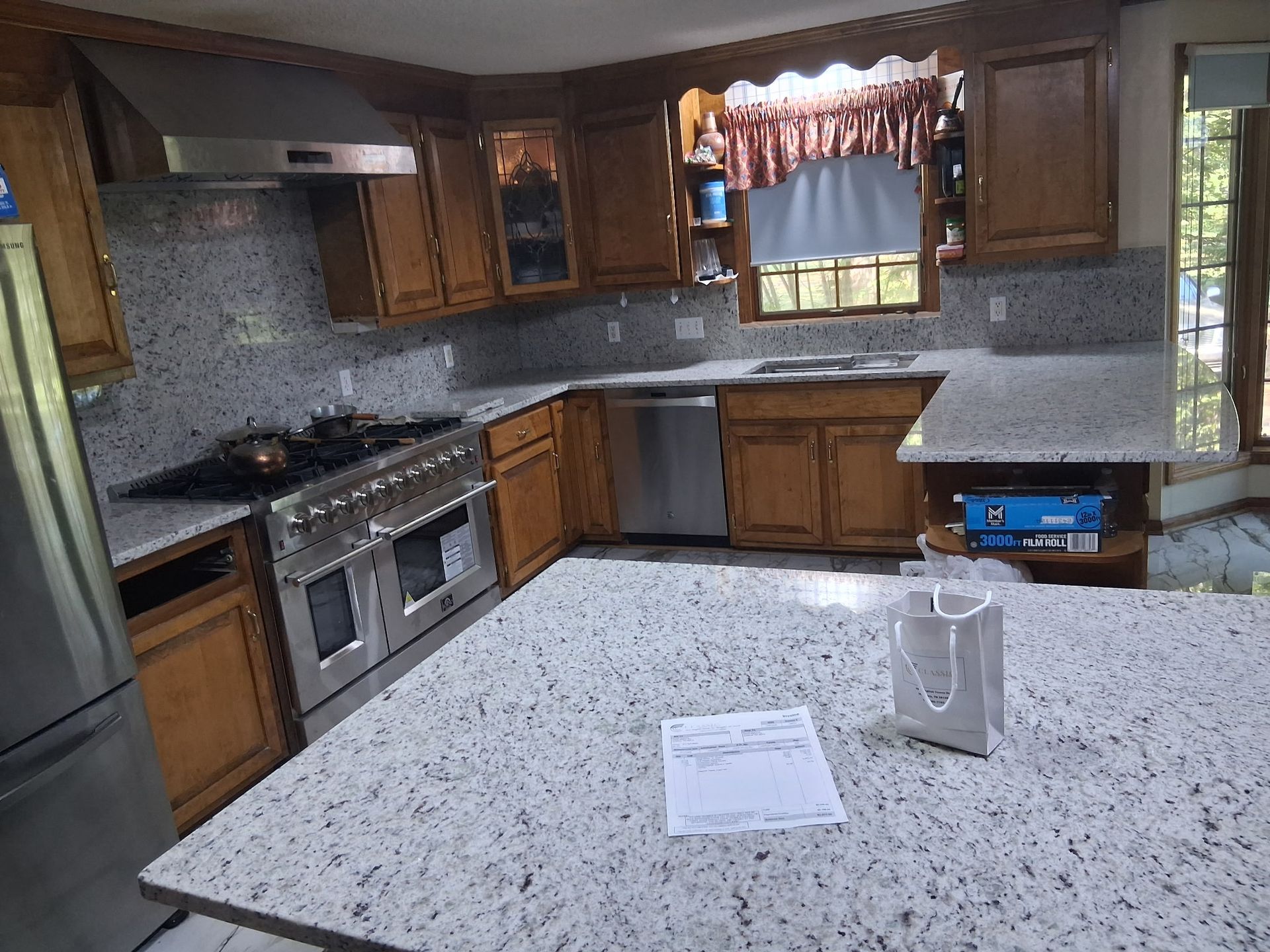 Modern kitchen with granite counters, wood cabinets, stainless appliances, and a window over the sink