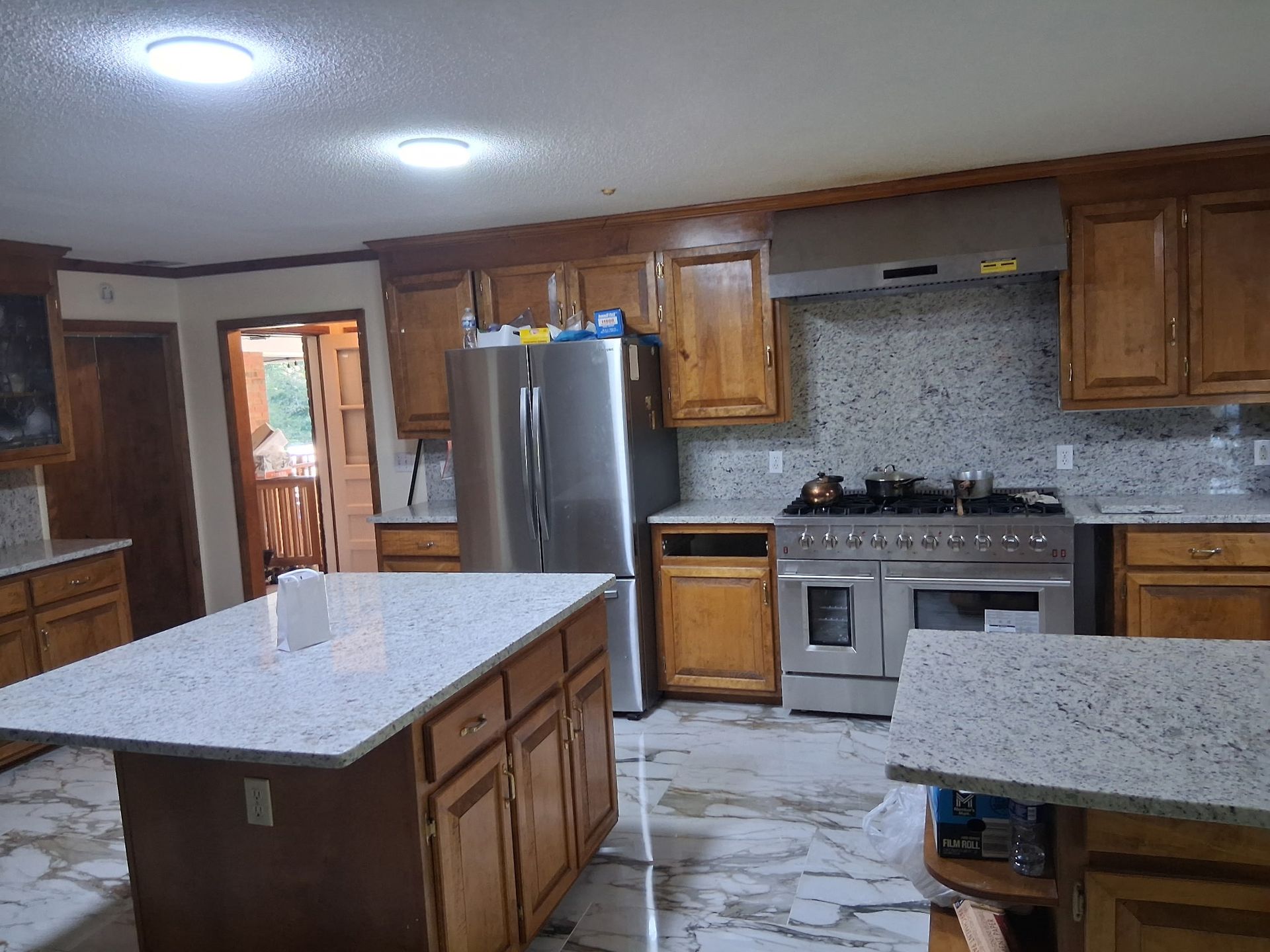 Modern kitchen with stainless steel fridge, island, wood cabinets, and gray tile backsplash