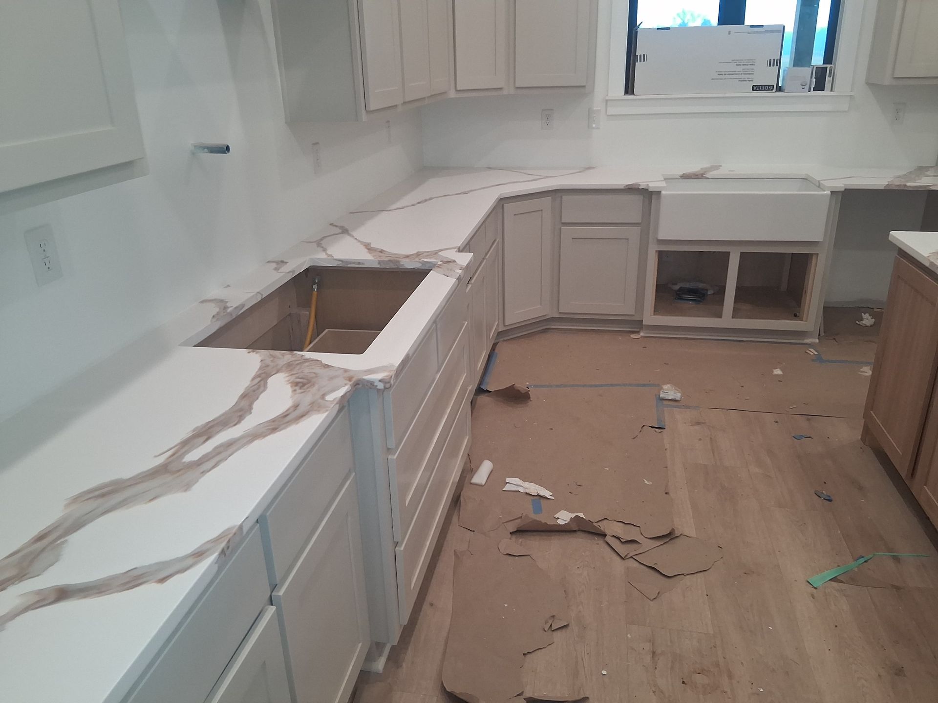 Damaged kitchen with torn-out sink, exposed cabinets, and debris on the floor