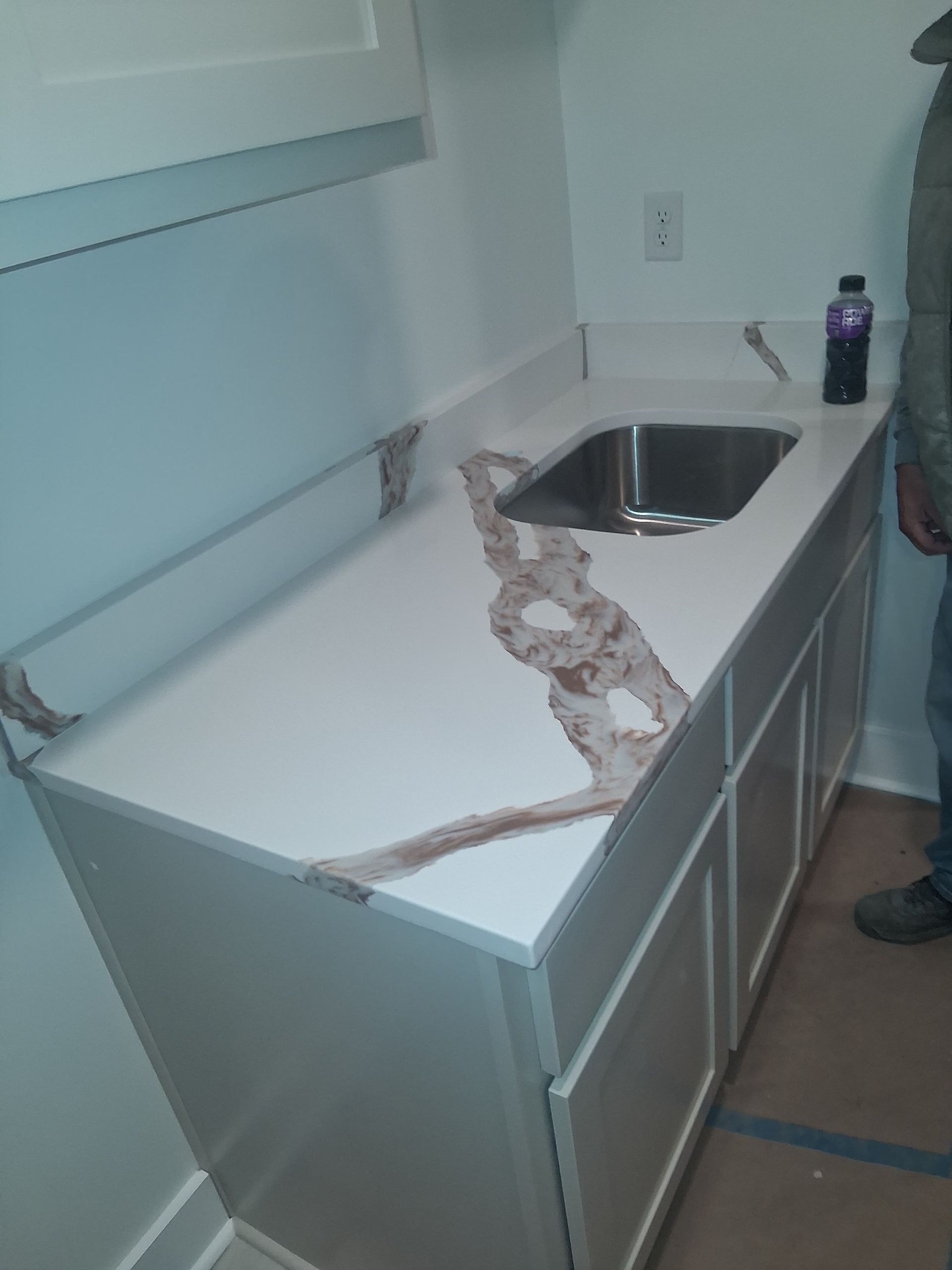 Damaged white countertop with a sink and a long crack in a small room under renovation