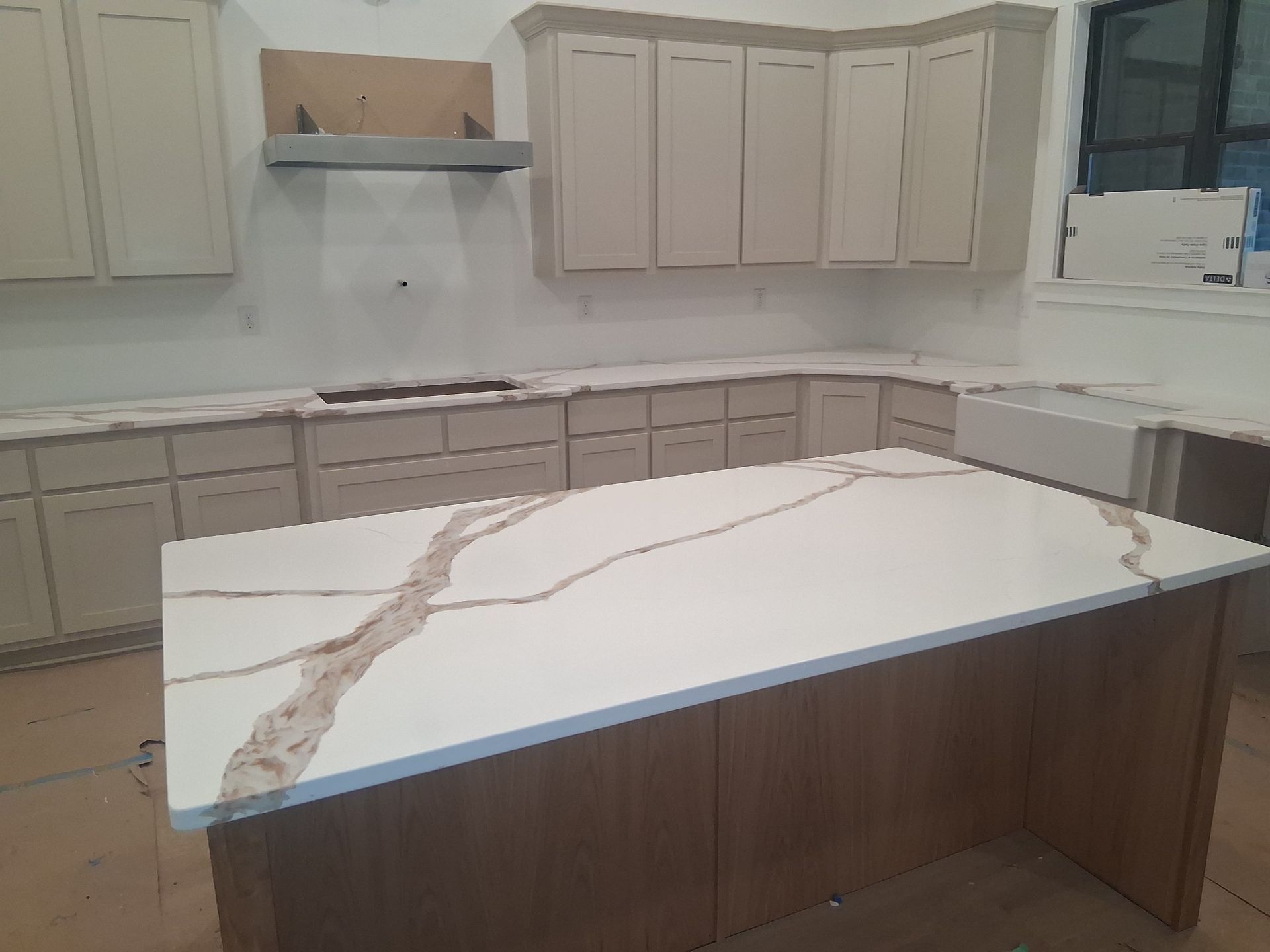 Modern kitchen with beige cabinets and a large white waterfall-edge island with wood paneling