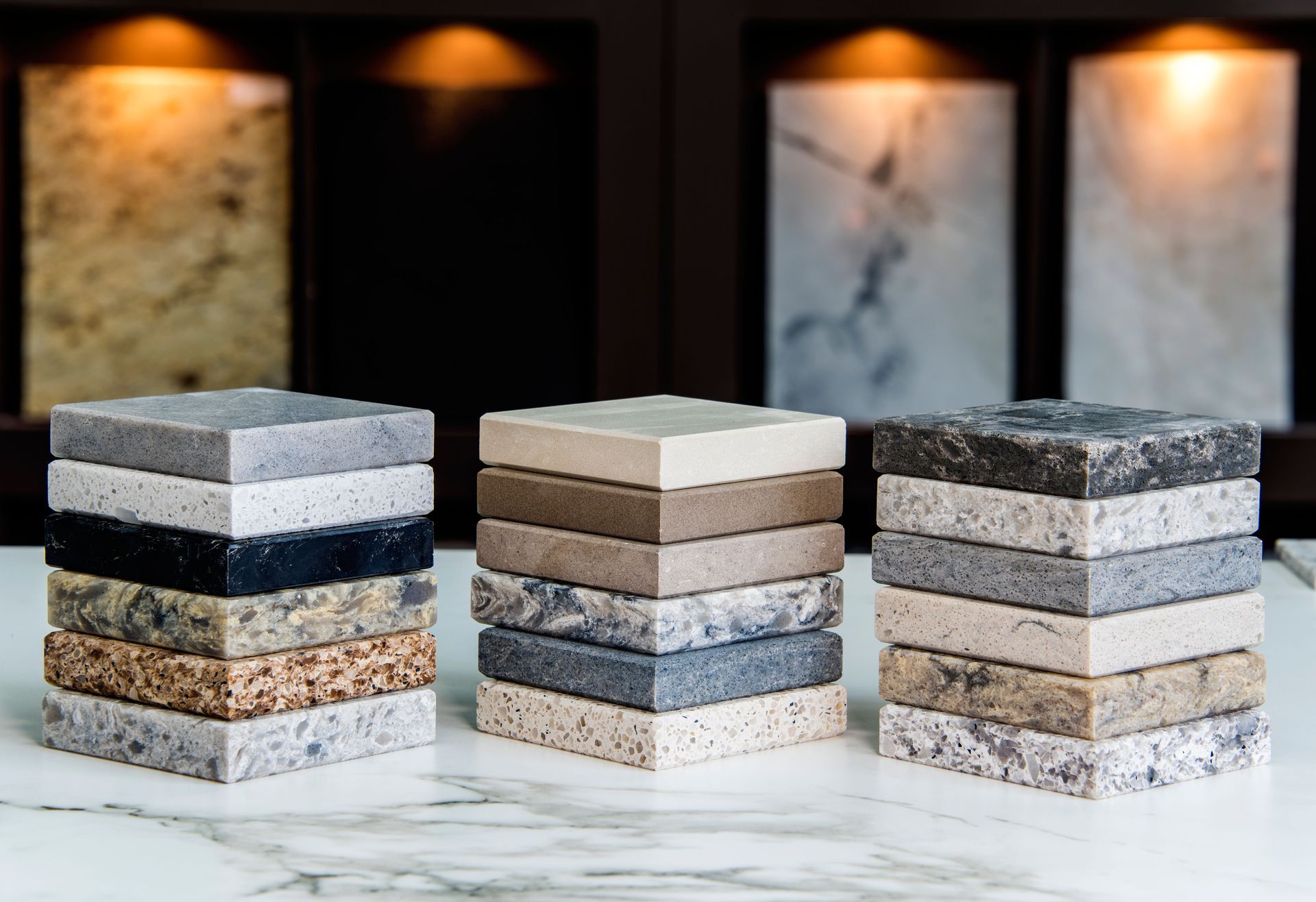 Stacks of countertop samples in various colors and textures, with cabinet displays in the background.