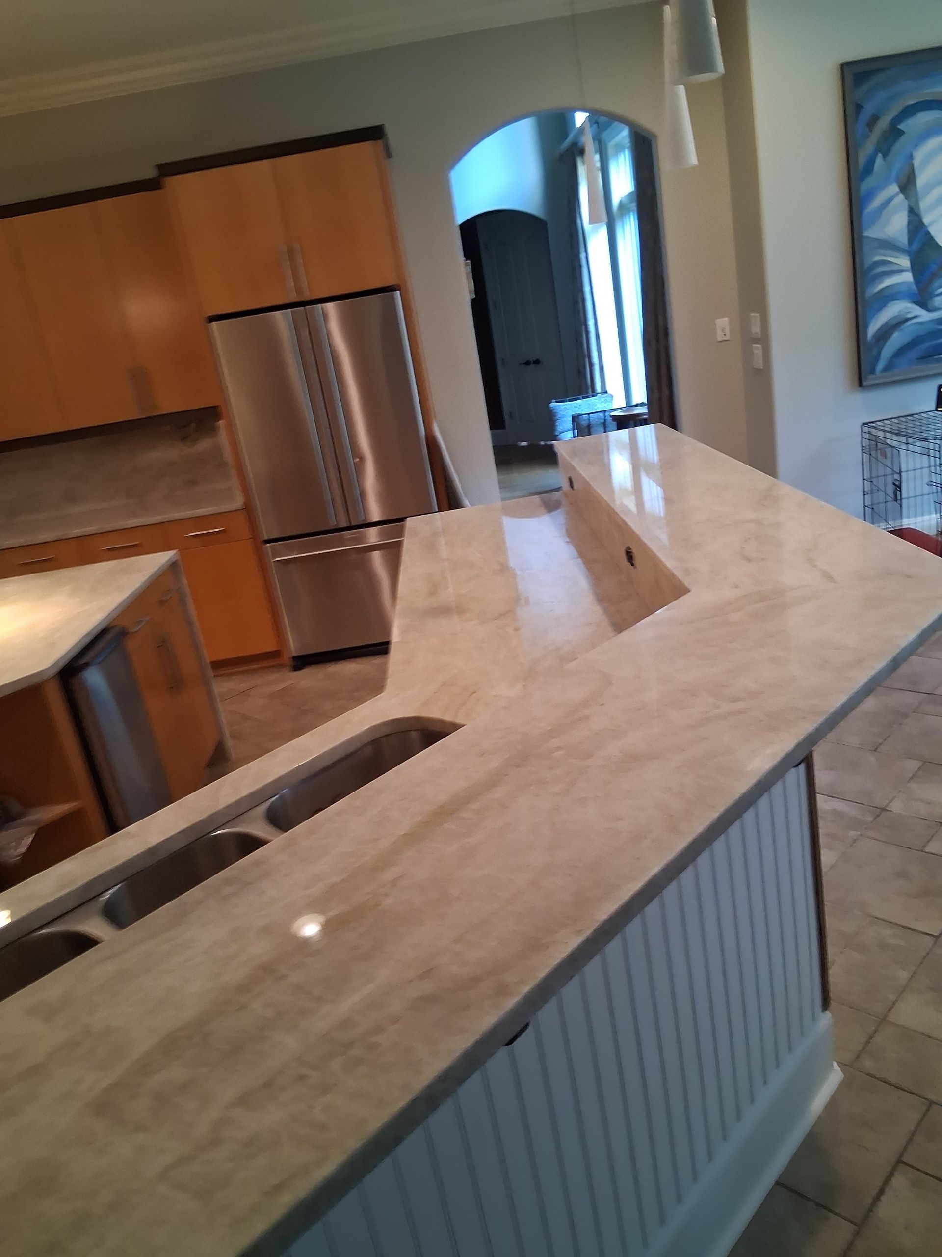Kitchen with beige countertop, stainless steel appliances, and an arched doorway in the background.