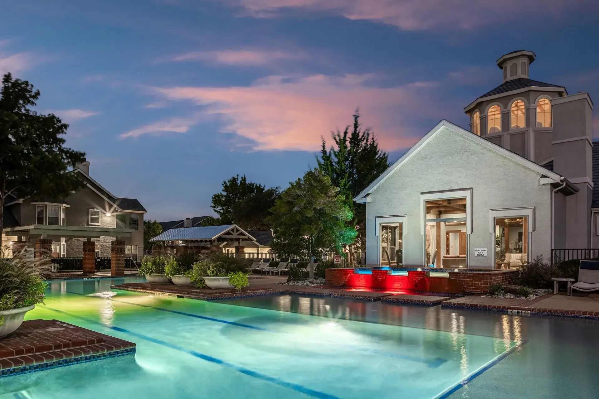 Resort-style swimming pool and spa with ambient lighting at dusk.