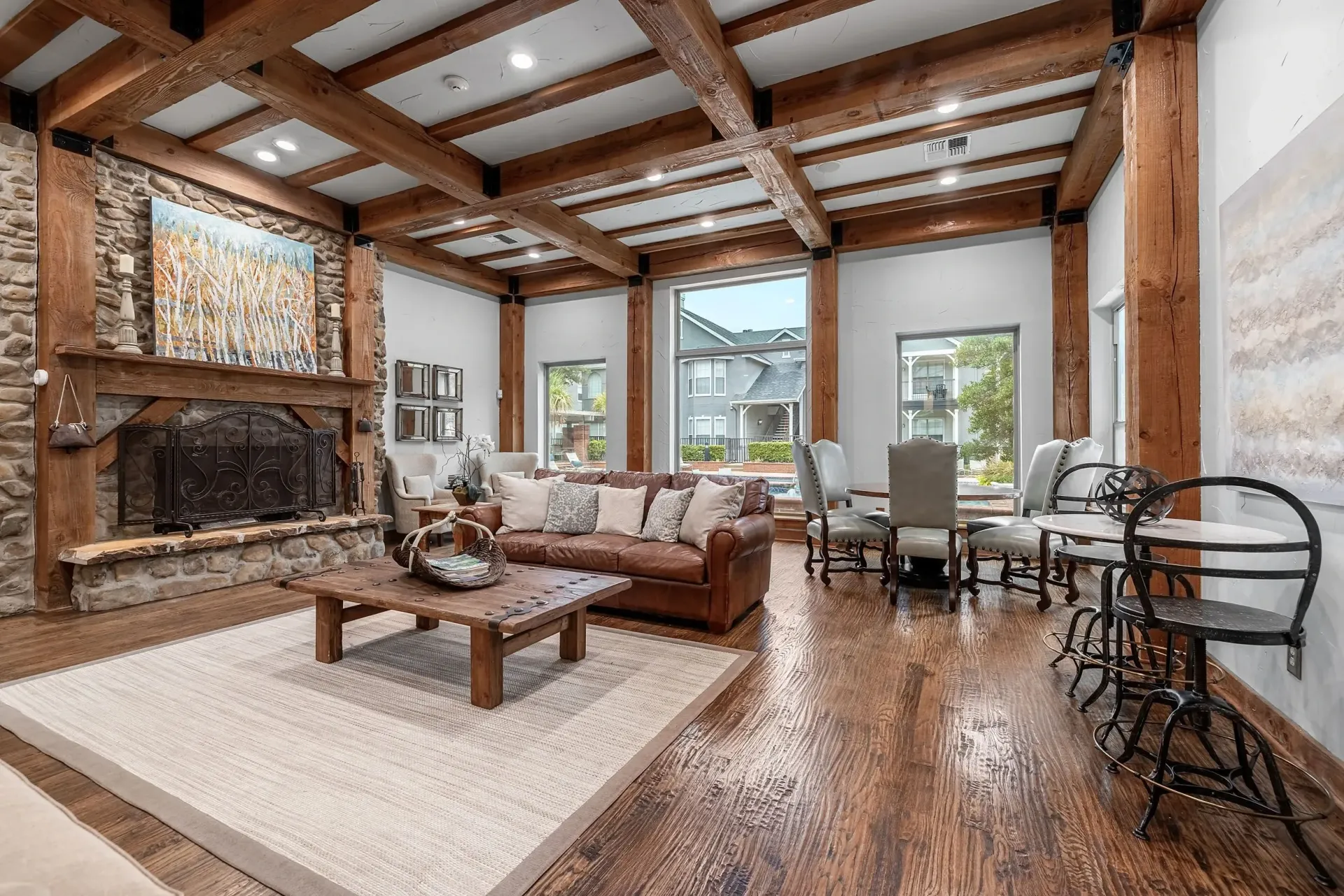 Spacious community lounge with stone fireplace, leather sofa, and dining area.