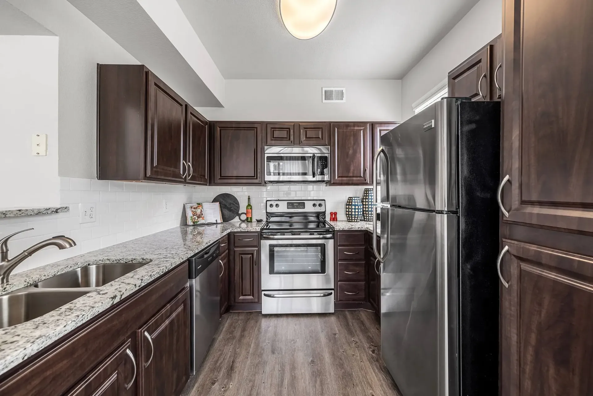 Modern kitchen with dark wood cabinets, granite countertops, and stainless steel appliances.