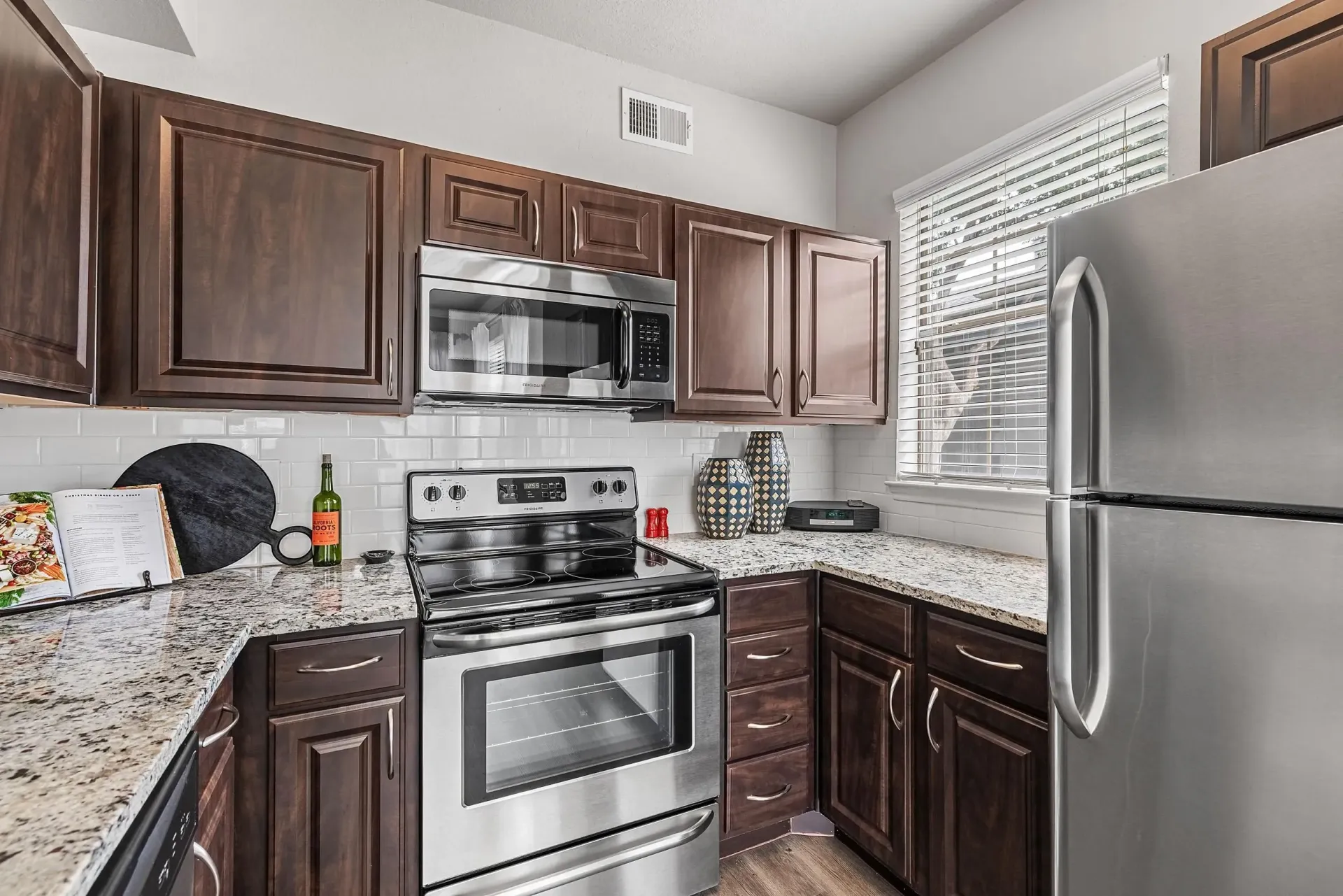 Modern kitchen with stainless steel appliances, granite countertops, and dark wood cabinets.
