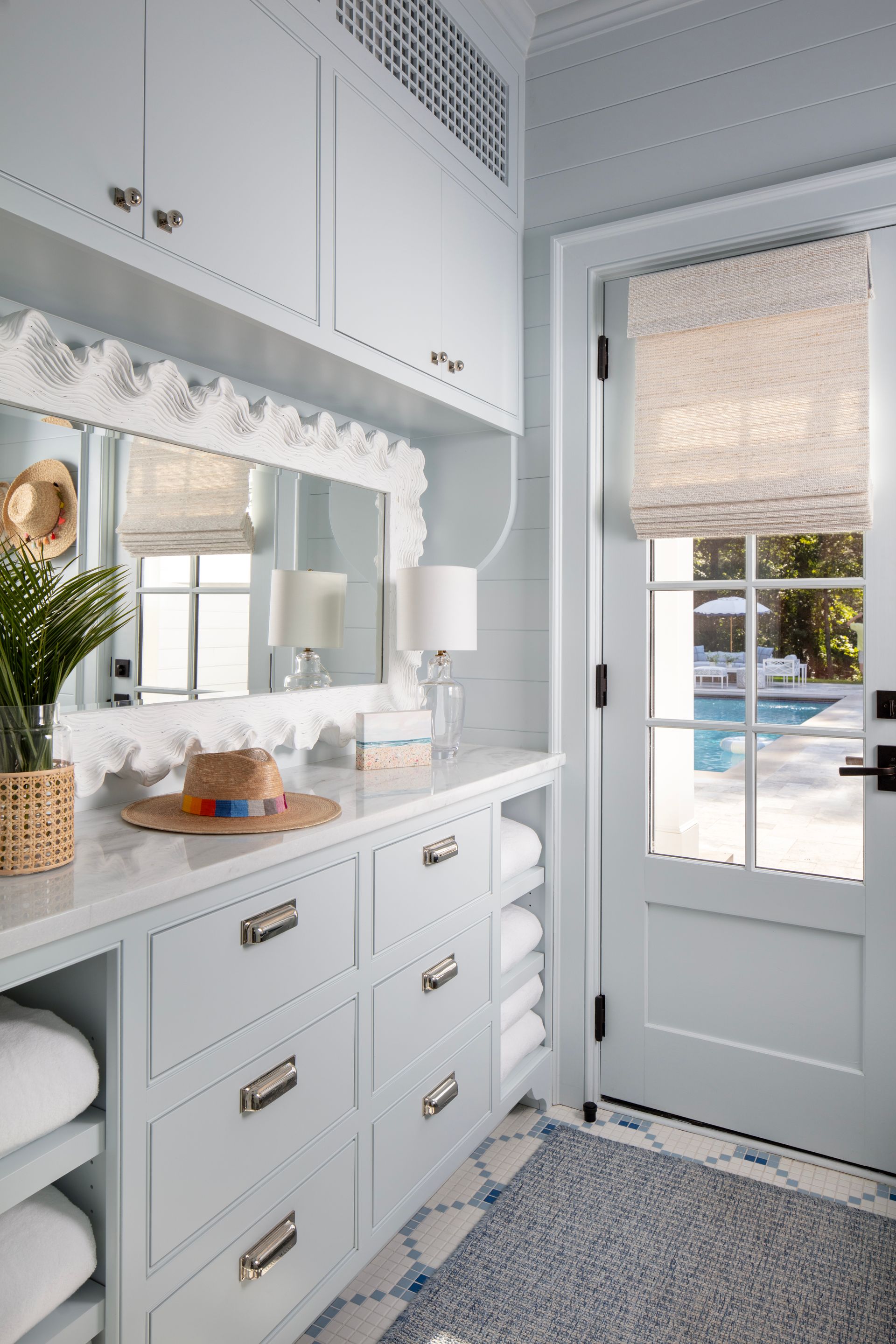 Light blue laundry room with cabinets, drawers, mirror, door to pool.