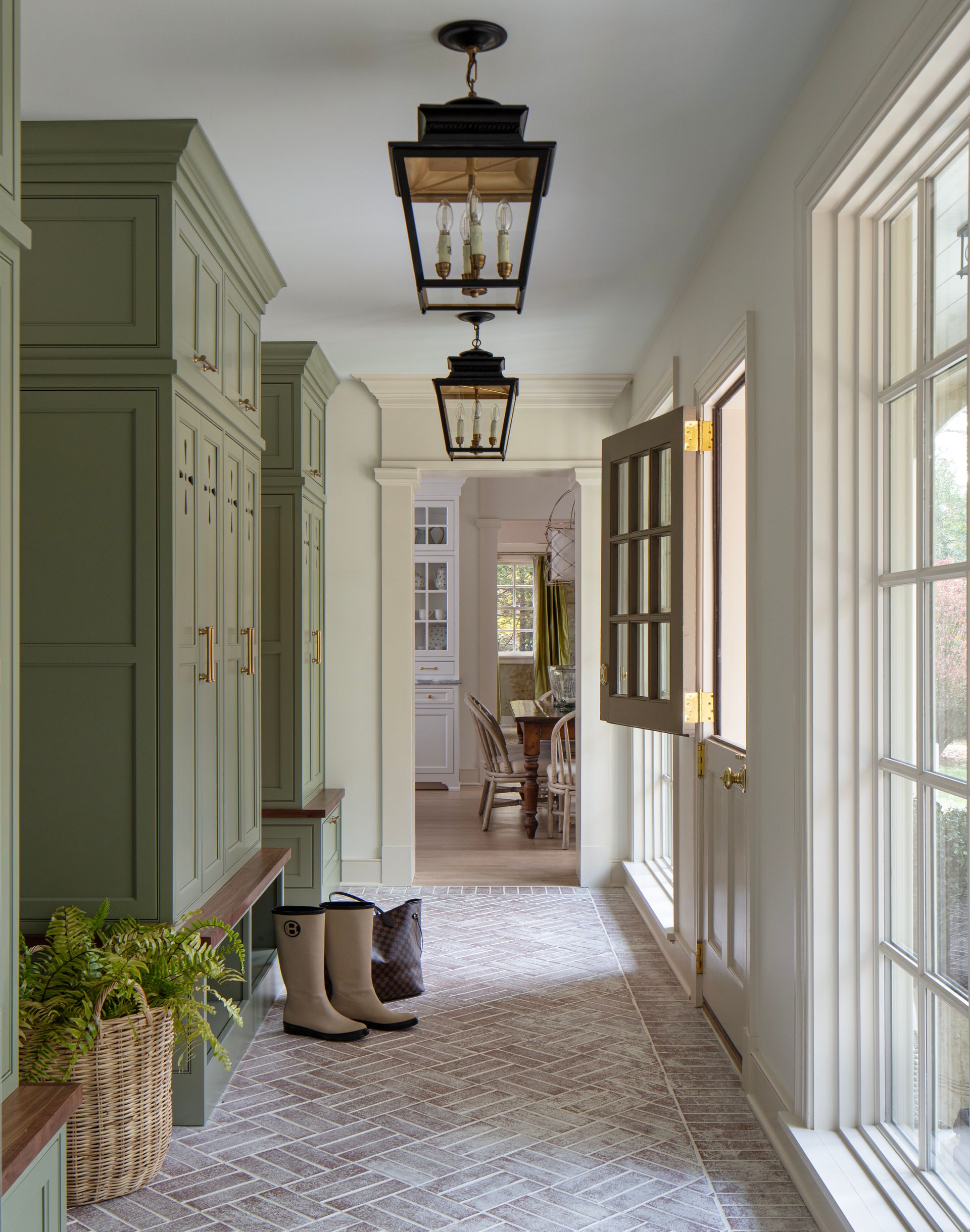 Hallway with sage green built-in storage, patterned rug, and lantern-style light fixtures.