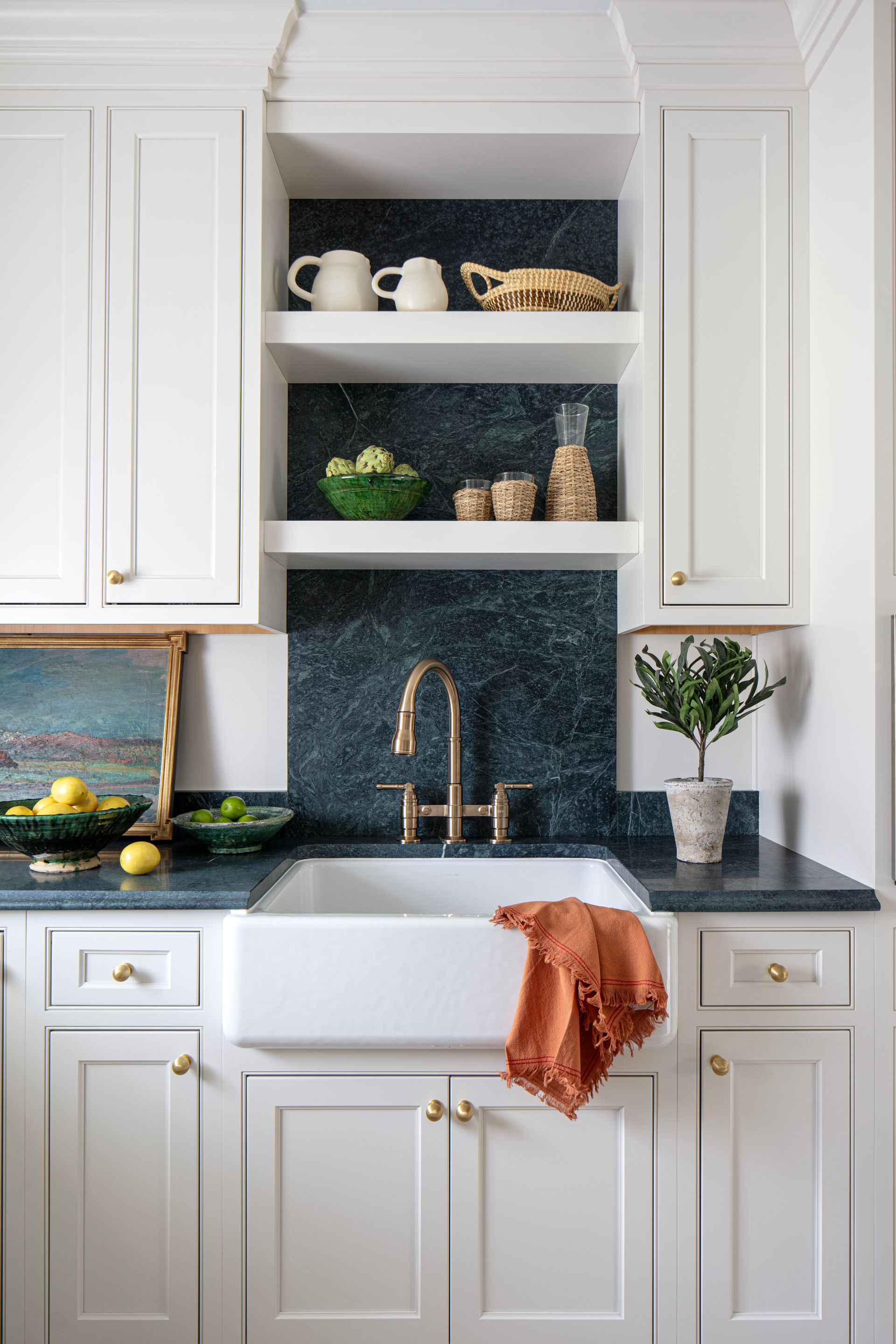 White kitchen with a farmhouse sink, open shelves, and blue-green backsplash.