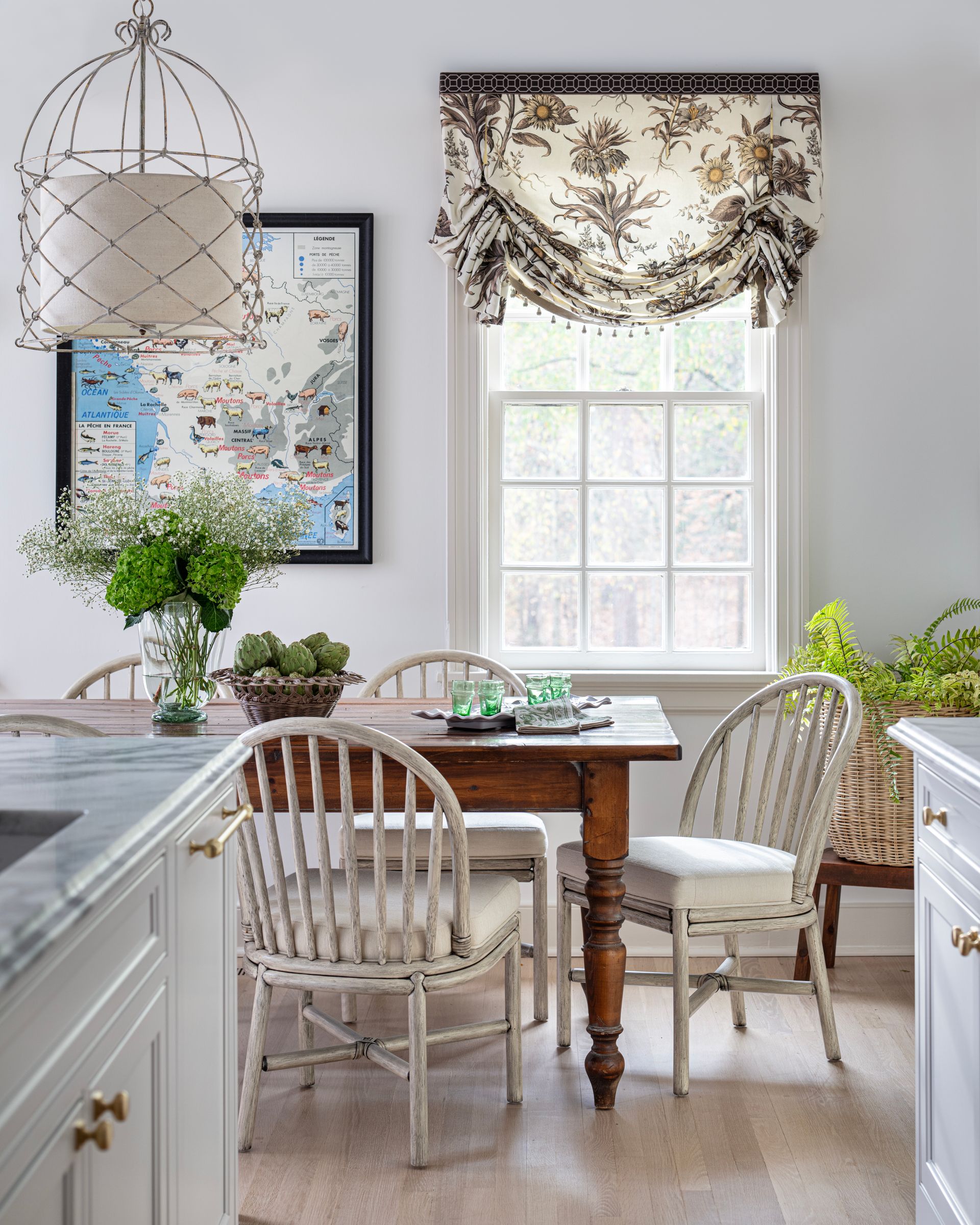 Dining room with wooden table, chairs, floral window treatment, and a hanging light fixture.