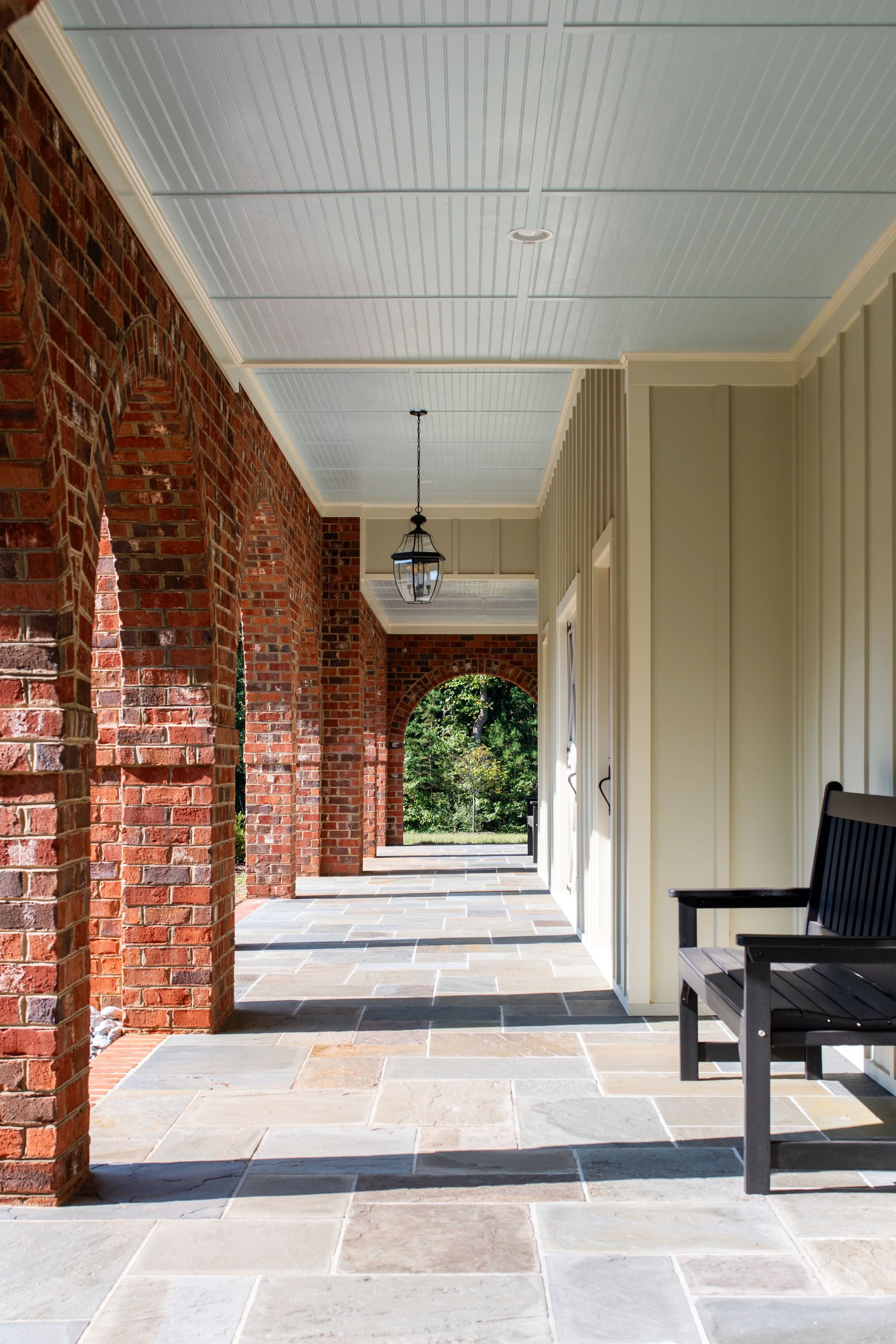 a long hallway with brick arches and a bench