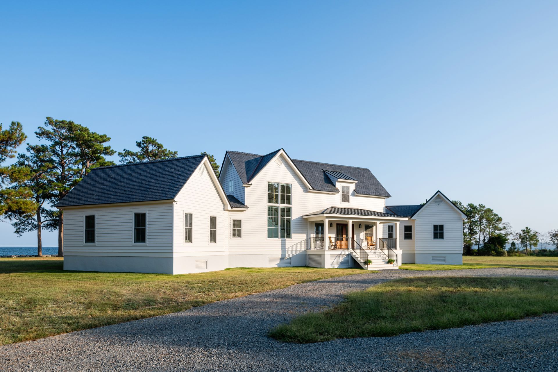 a white house with a black roof sits in the middle of a grassy field