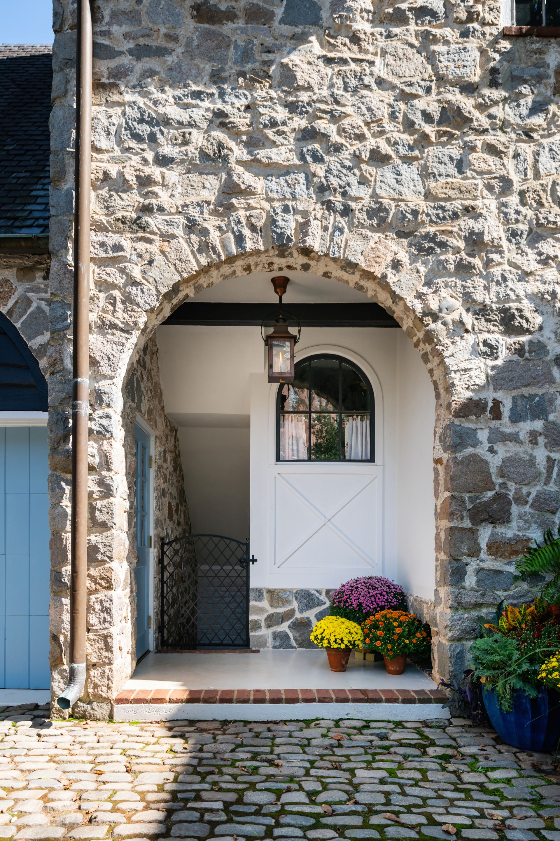 a stone building with a white door and flowers in front of it