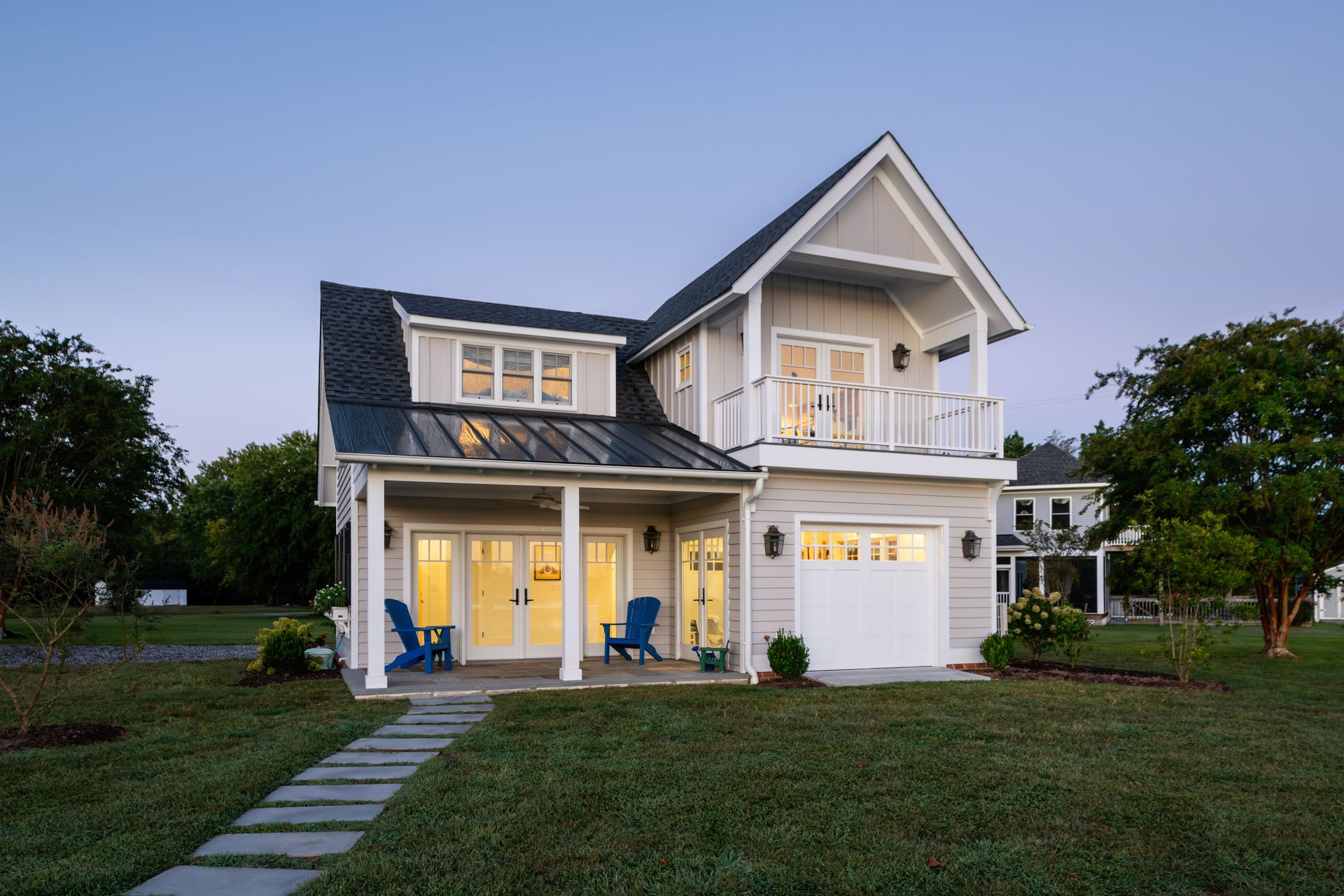 a white house with blue chairs on the porch