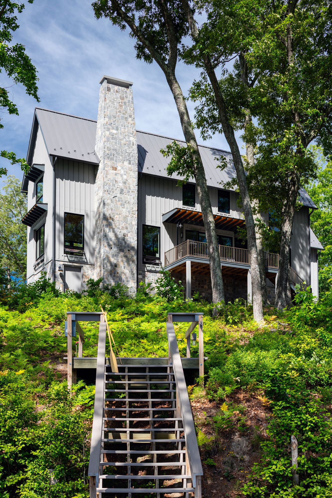 A house with stairs leading up to it and trees in front of it.