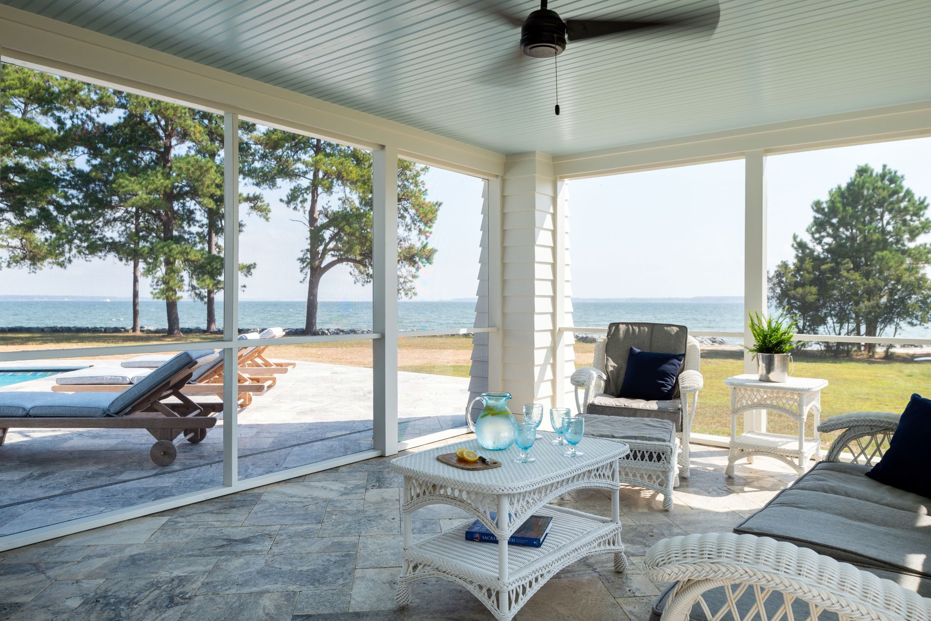 a screened in porch with a view of the ocean