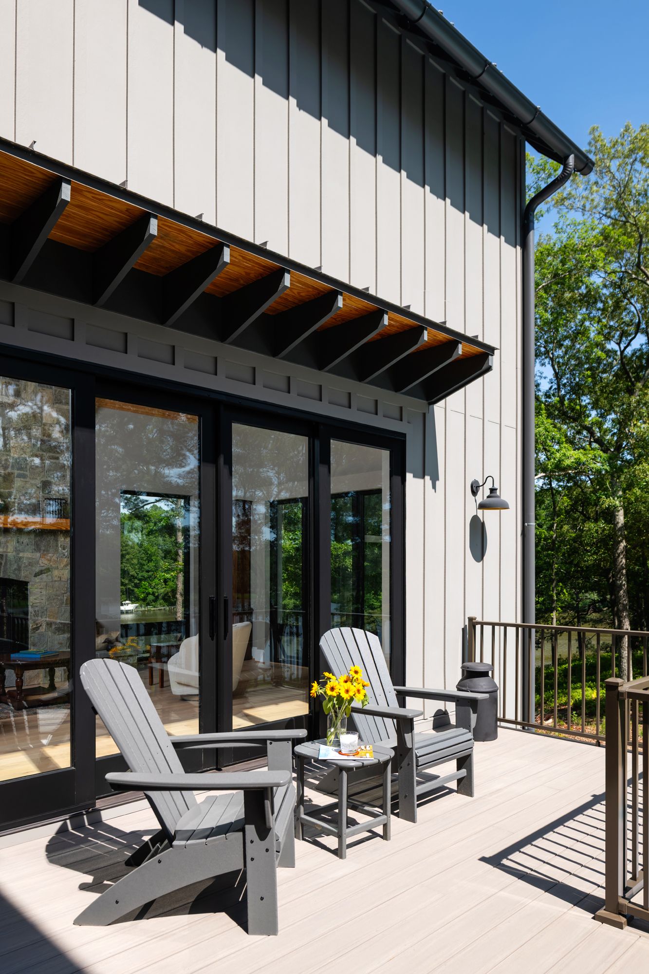 A deck with chairs and a table in front of a house.