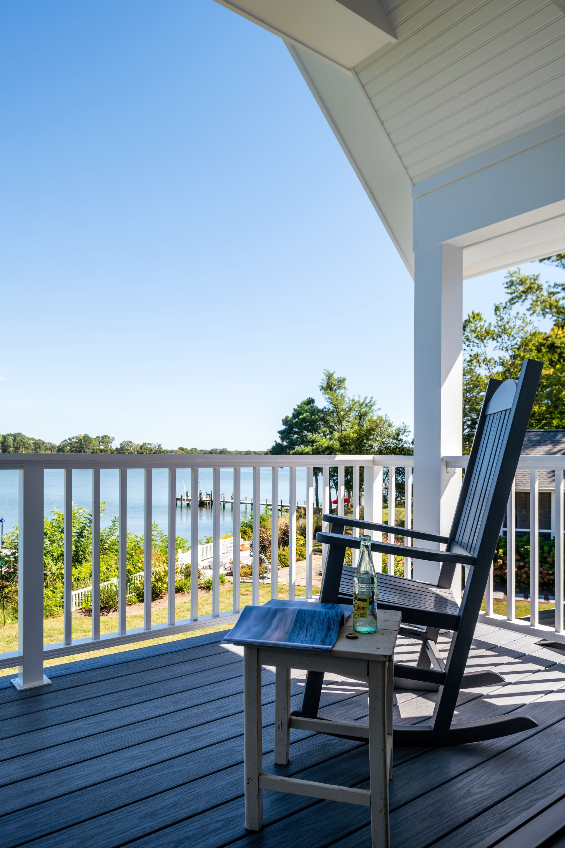 a rocking chair sits on a deck overlooking the water