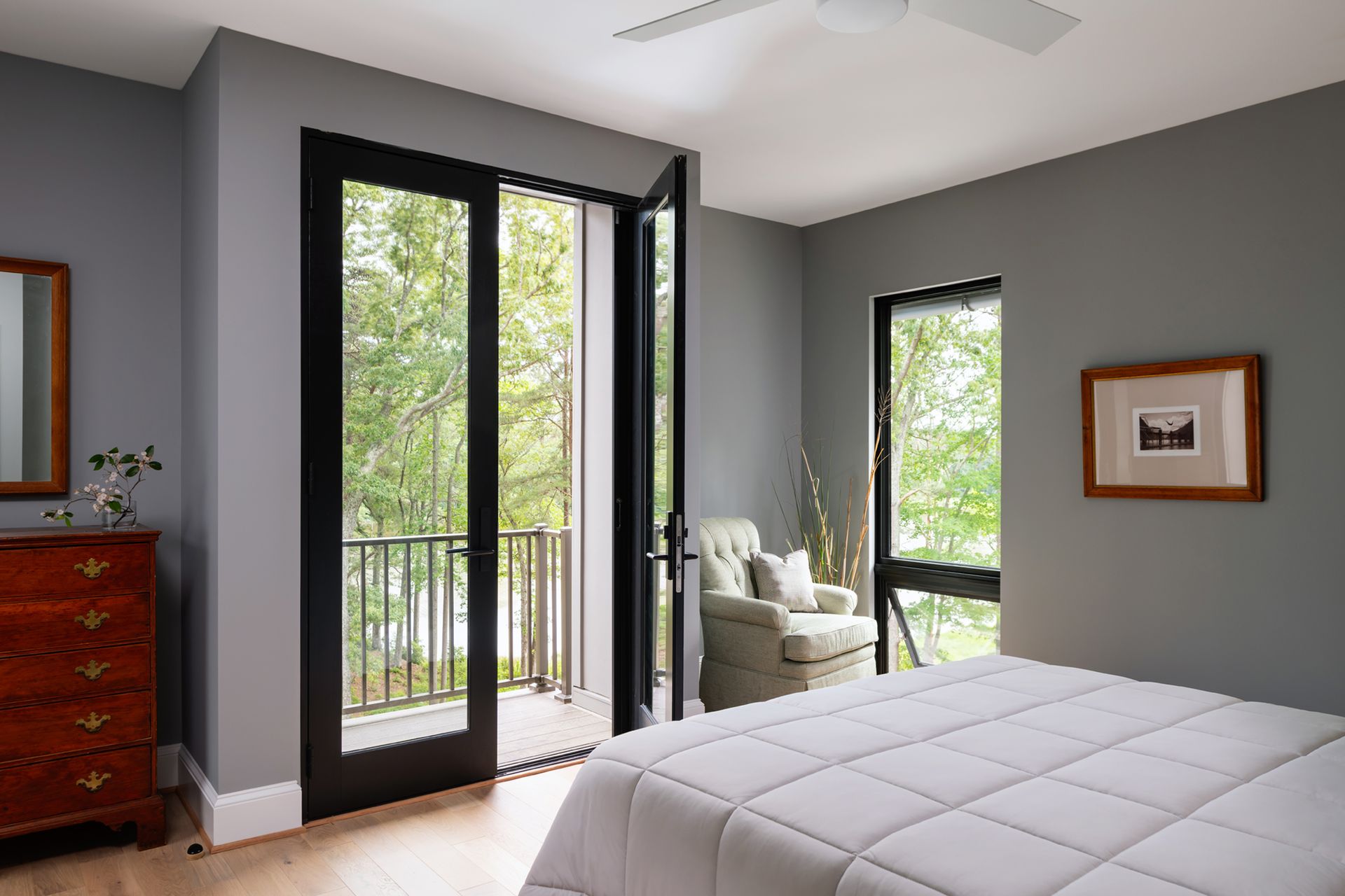 A bedroom with a bed , dresser , chair and sliding glass doors leading to a balcony.