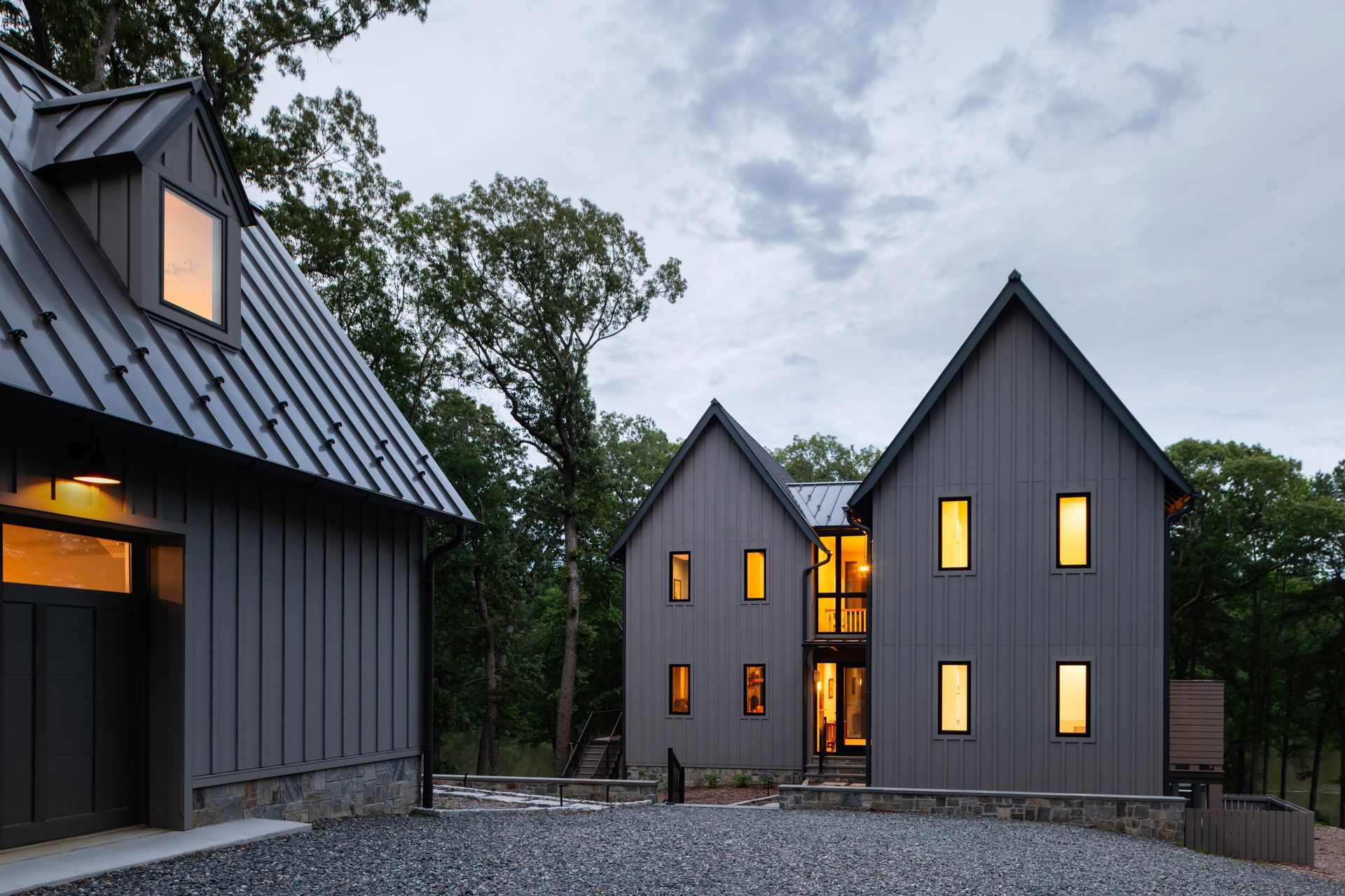 A couple of houses sitting next to each other on top of a gravel driveway.