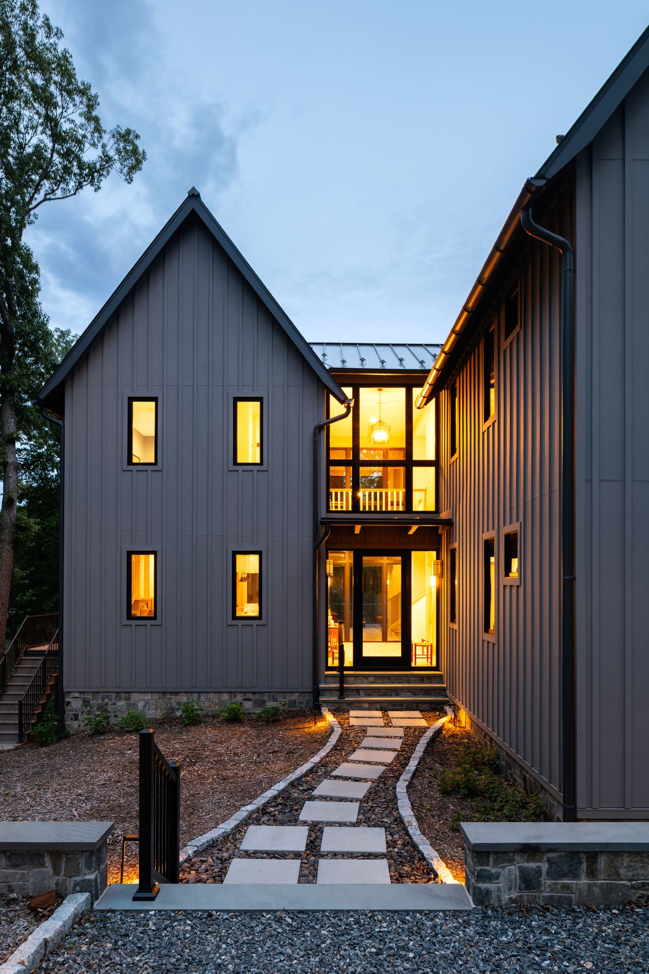 A large gray house with a stone walkway leading to it.