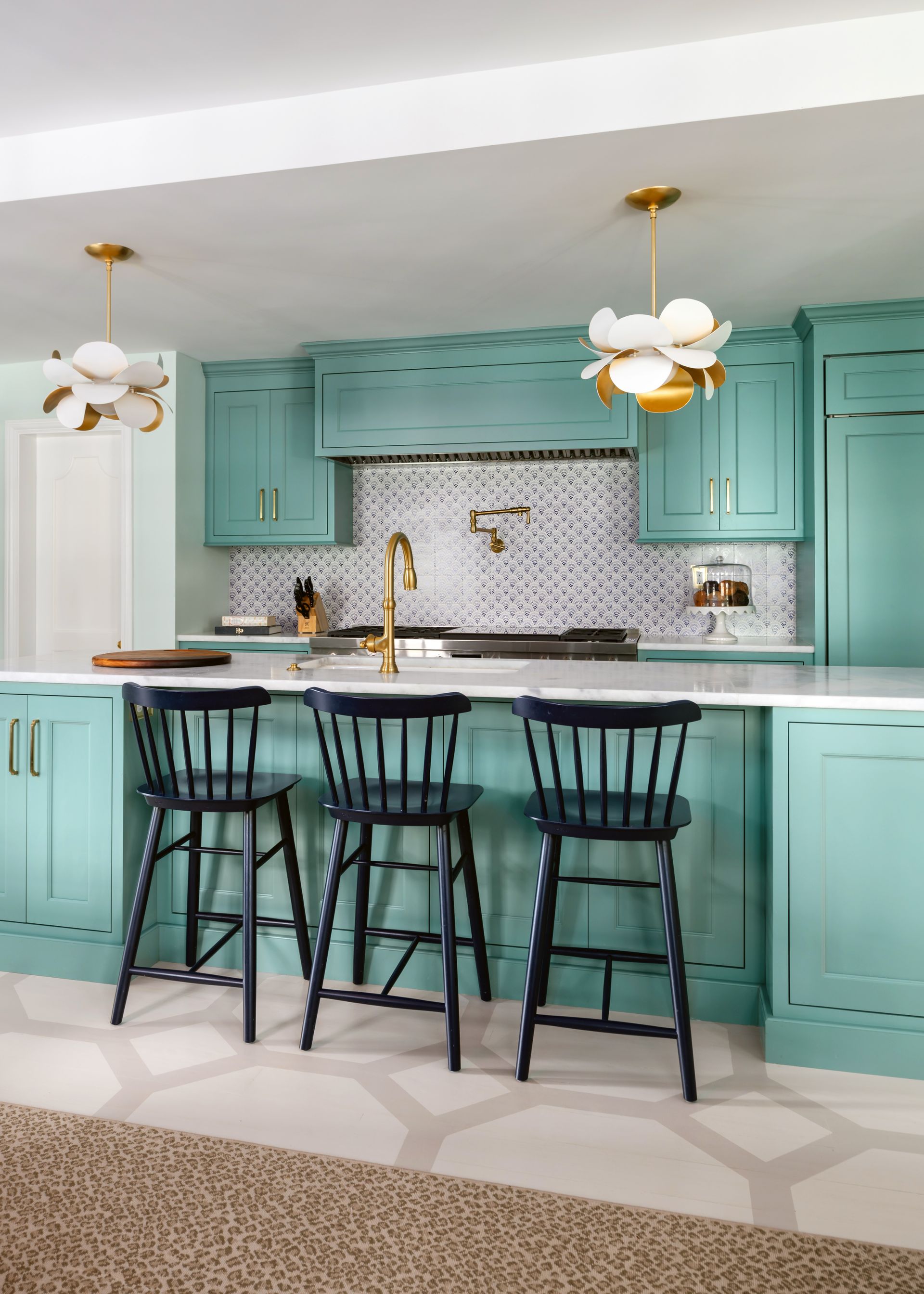 a kitchen with green cabinets and black chairs