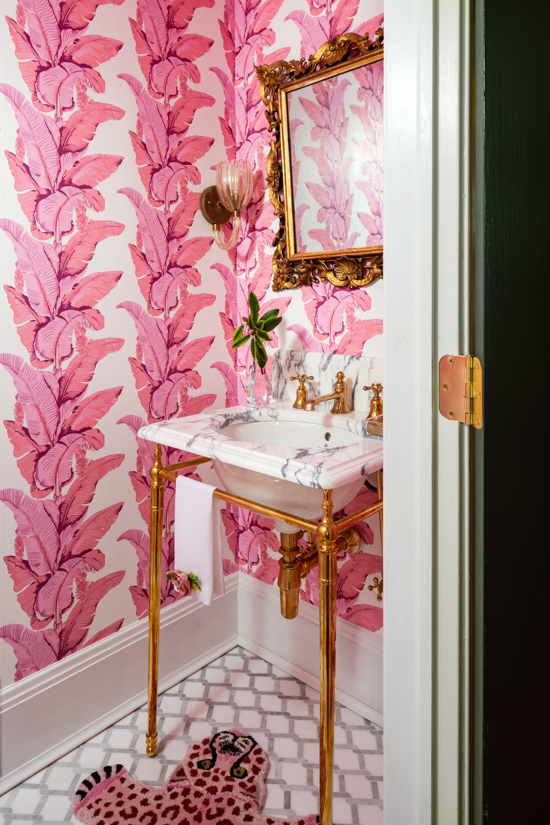a bathroom with pink wallpaper and a gold sink