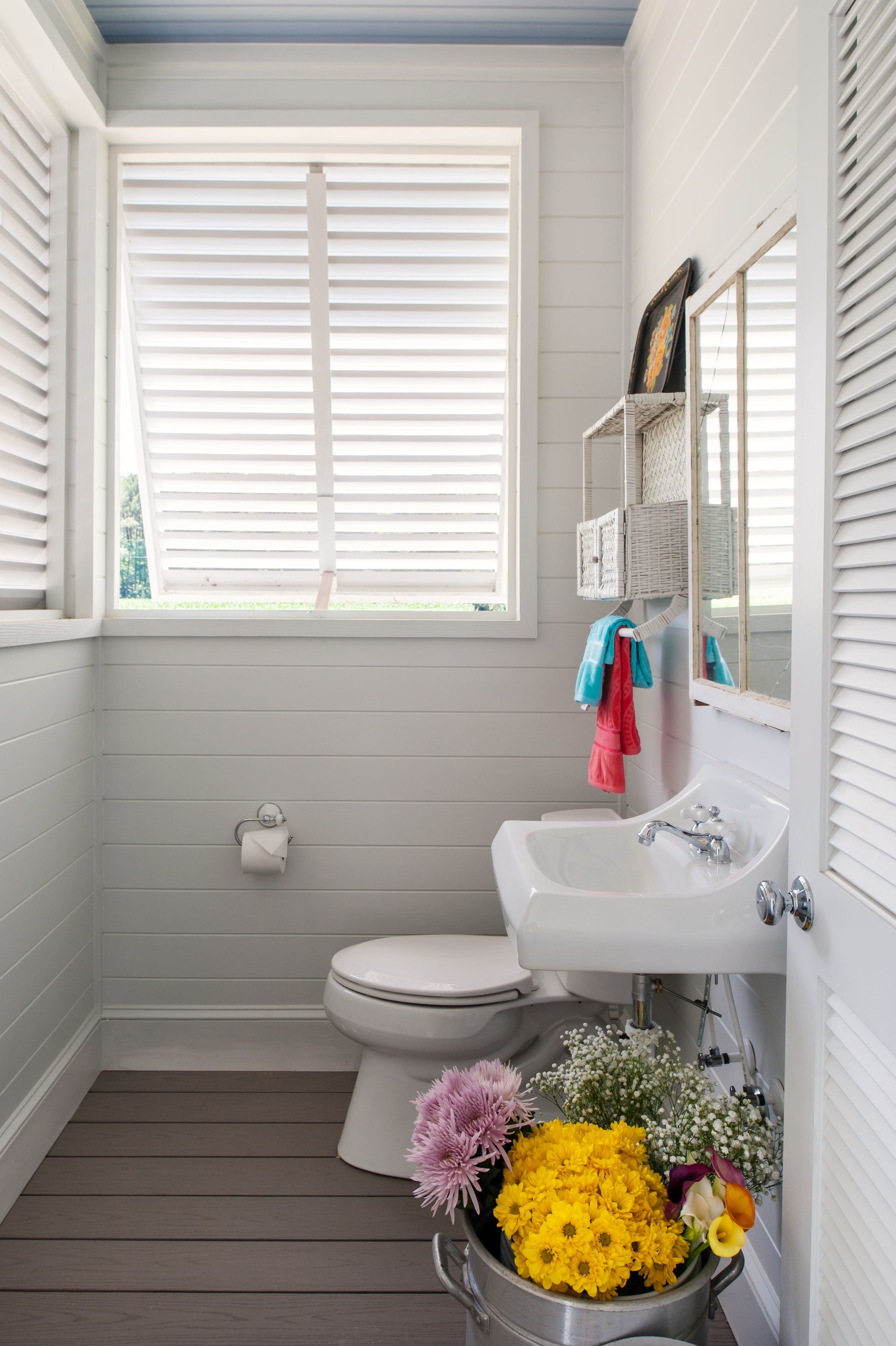 a bathroom with a toilet sink and a bucket of flowers
