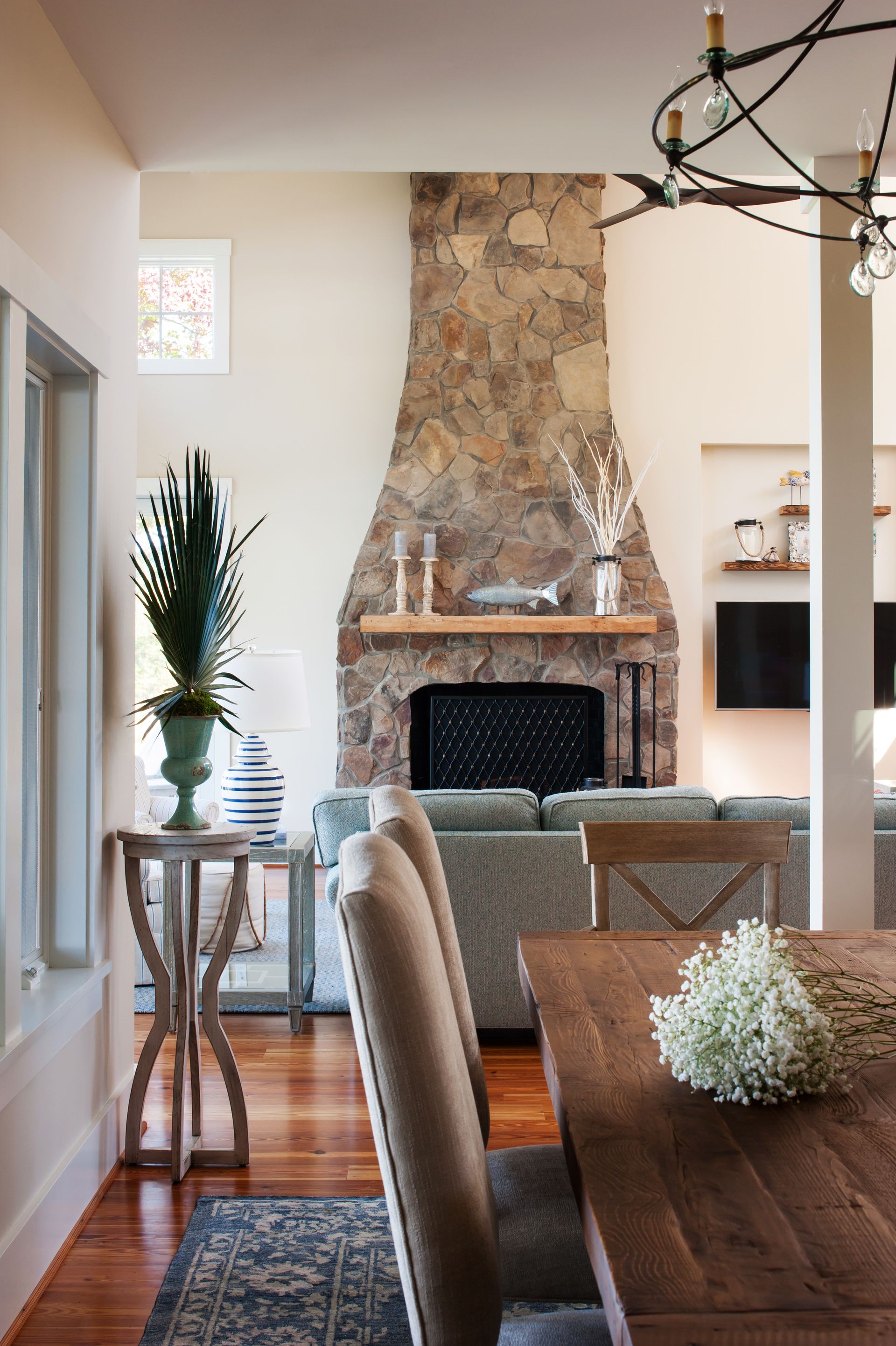 a living room with a stone fireplace and a dining table