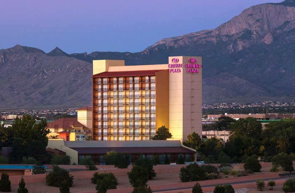 A large hotel with mountains in the background is lit up at night