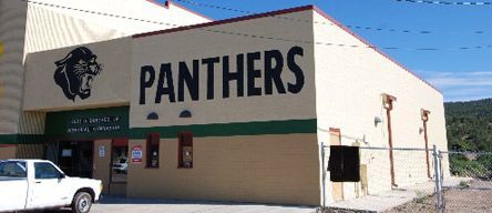 A white truck is parked in front of a building that says panthers