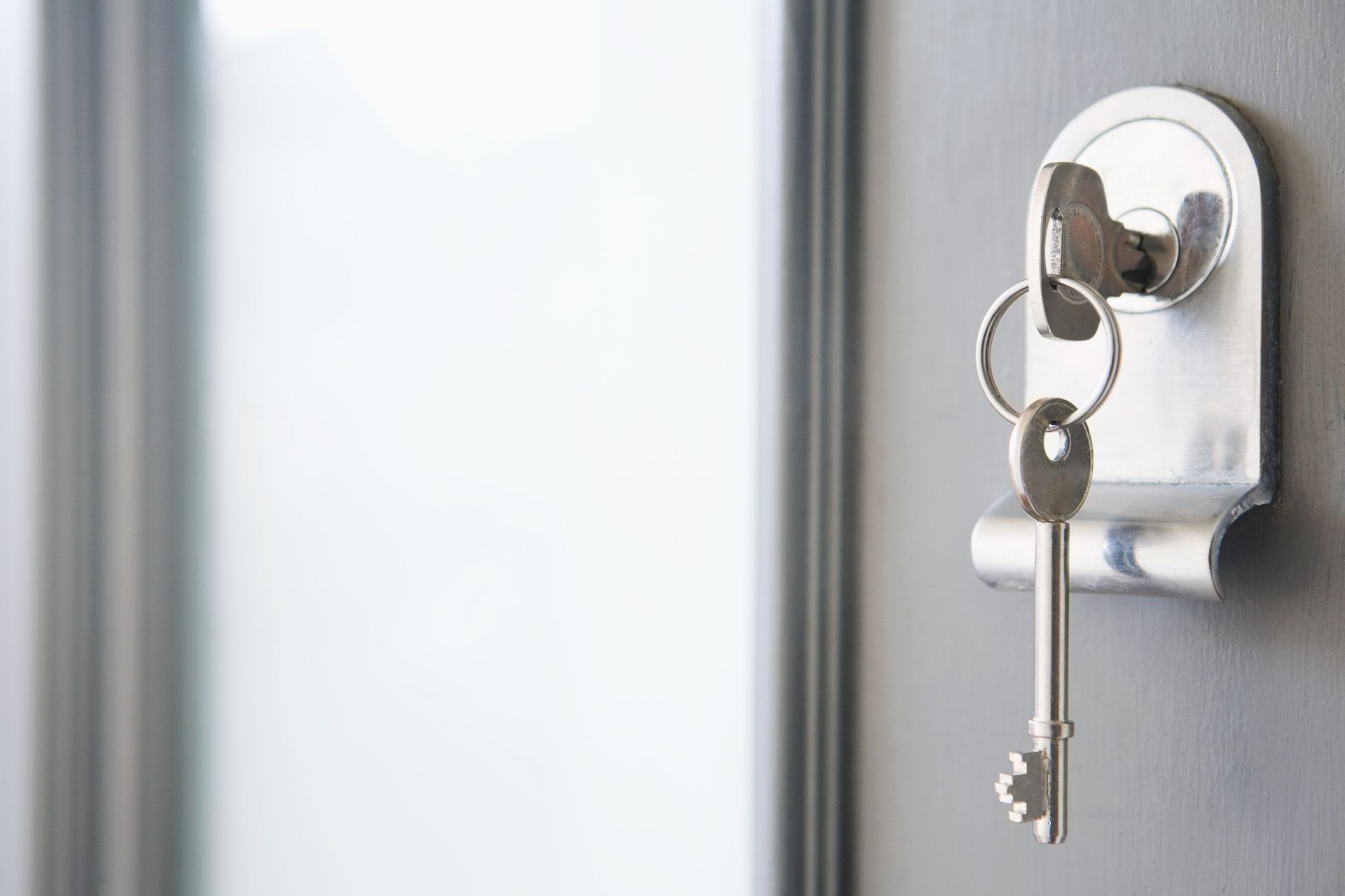 A pair of keys hanging from a keyhole on a door.
