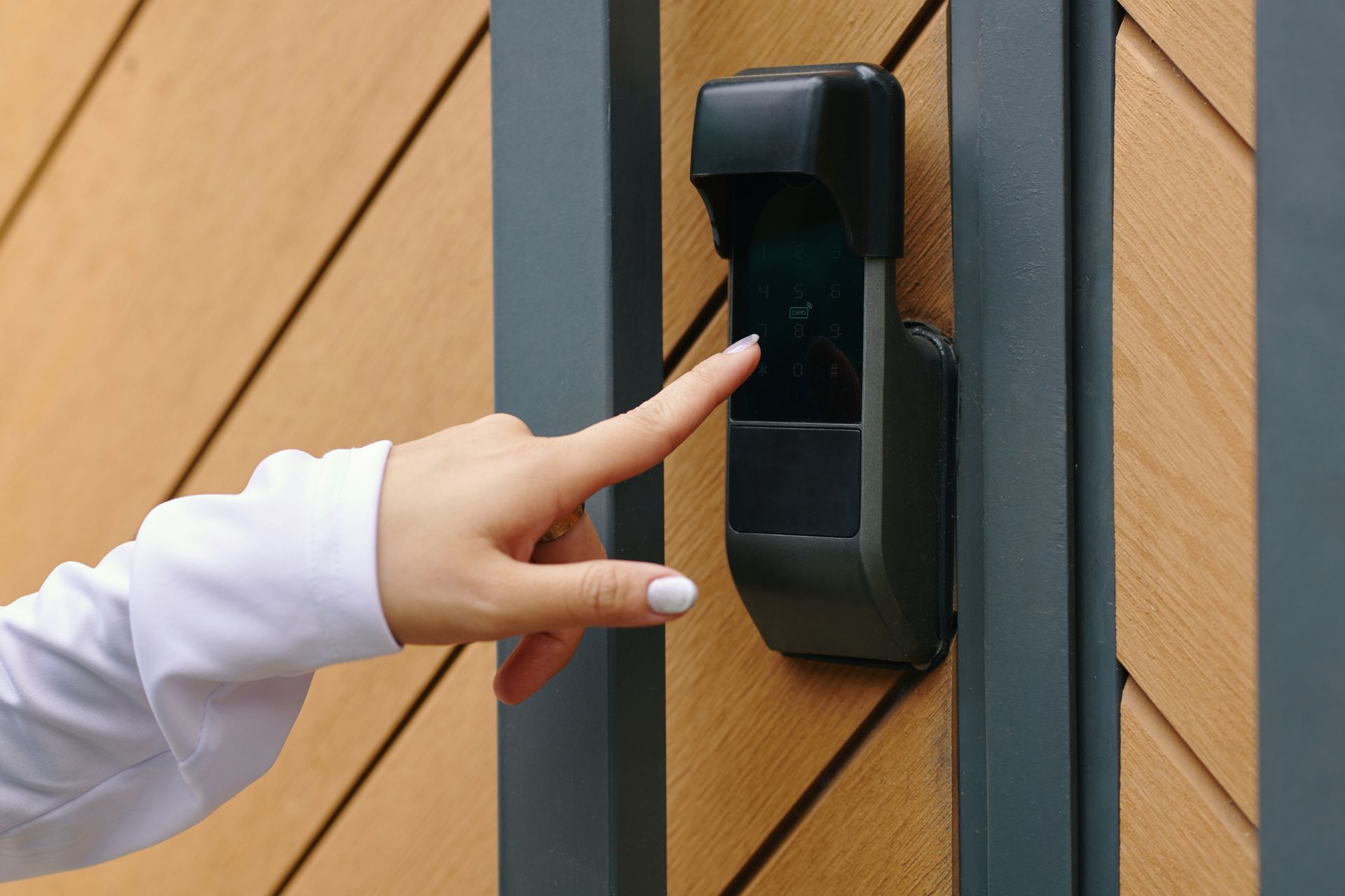 A person is pressing a button on a gate with their finger.