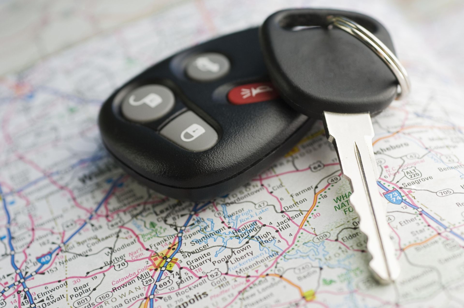 A car key is laying on top of a map.