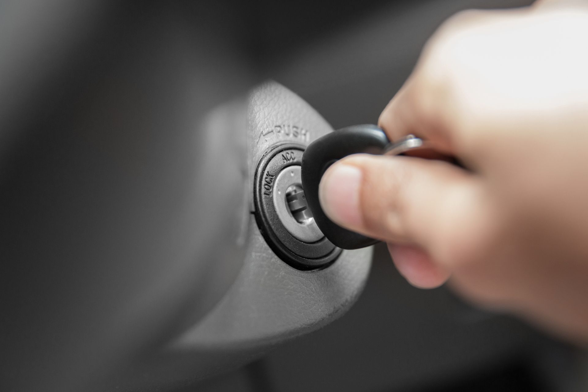 A hand turning a metal car key inside an ignition cylinder.