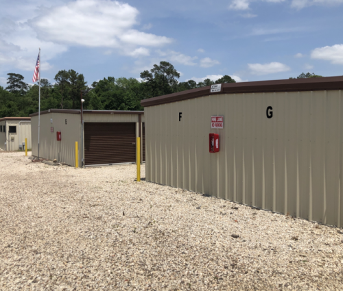Gravel lot with beige storage units labeled F and G, and a fire extinguisher cabinet on the wall