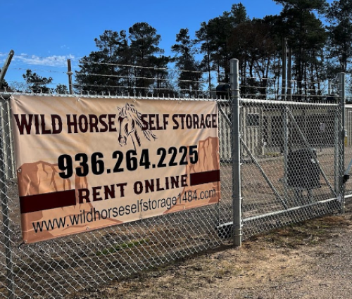 Wild Horse Self Storage banner on chain-link fence with phone number and rent online text