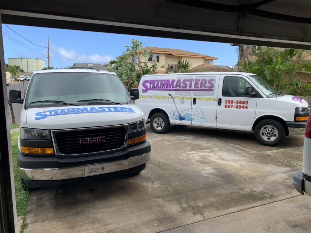 Two vans are parked in a garage next to each other.