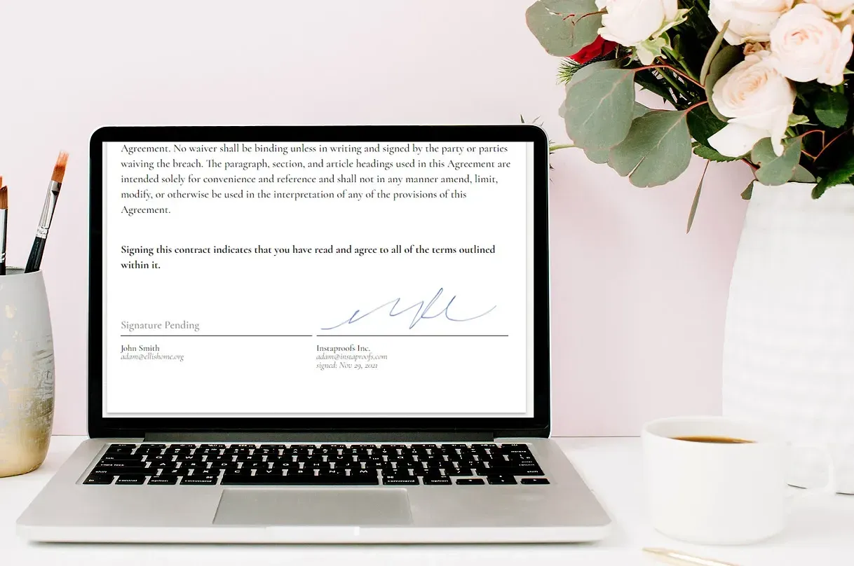 Laptop displaying a document, with flowers and coffee on a white desk.