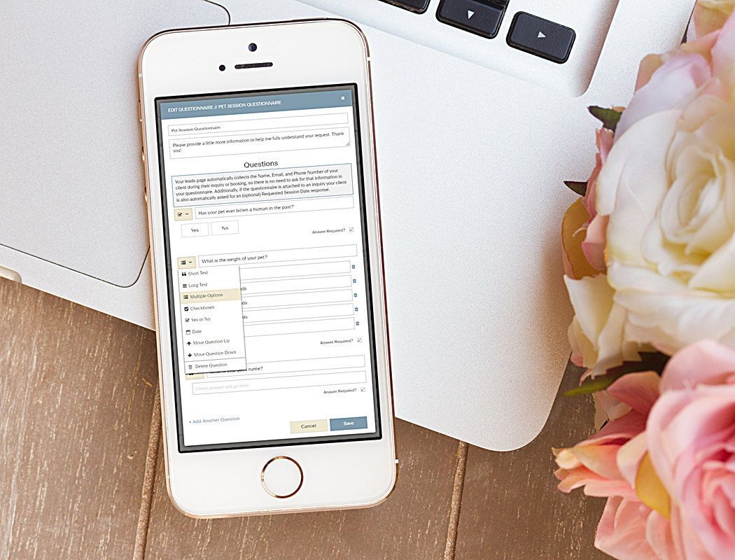 Smartphone displaying a form on a laptop, with pink and white flowers on a wooden table.