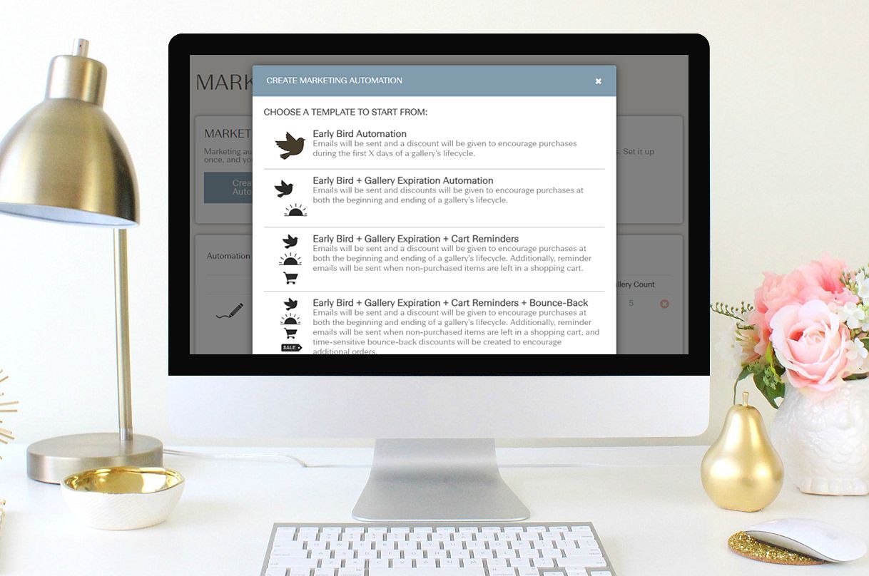 Computer screen displaying a pop-up menu with text and icons, desk with lamp, flowers, and keyboard.