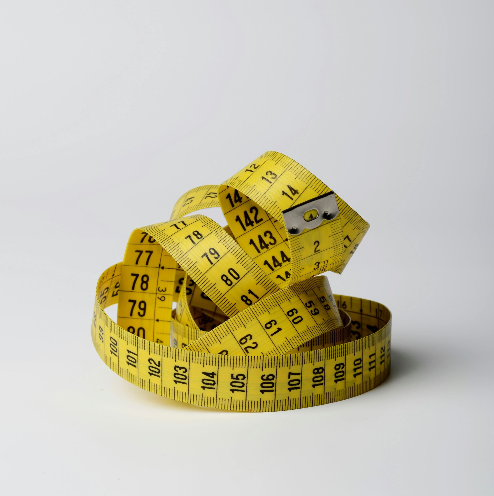 Yellow coiled measuring tape with black numbers, against a white background.