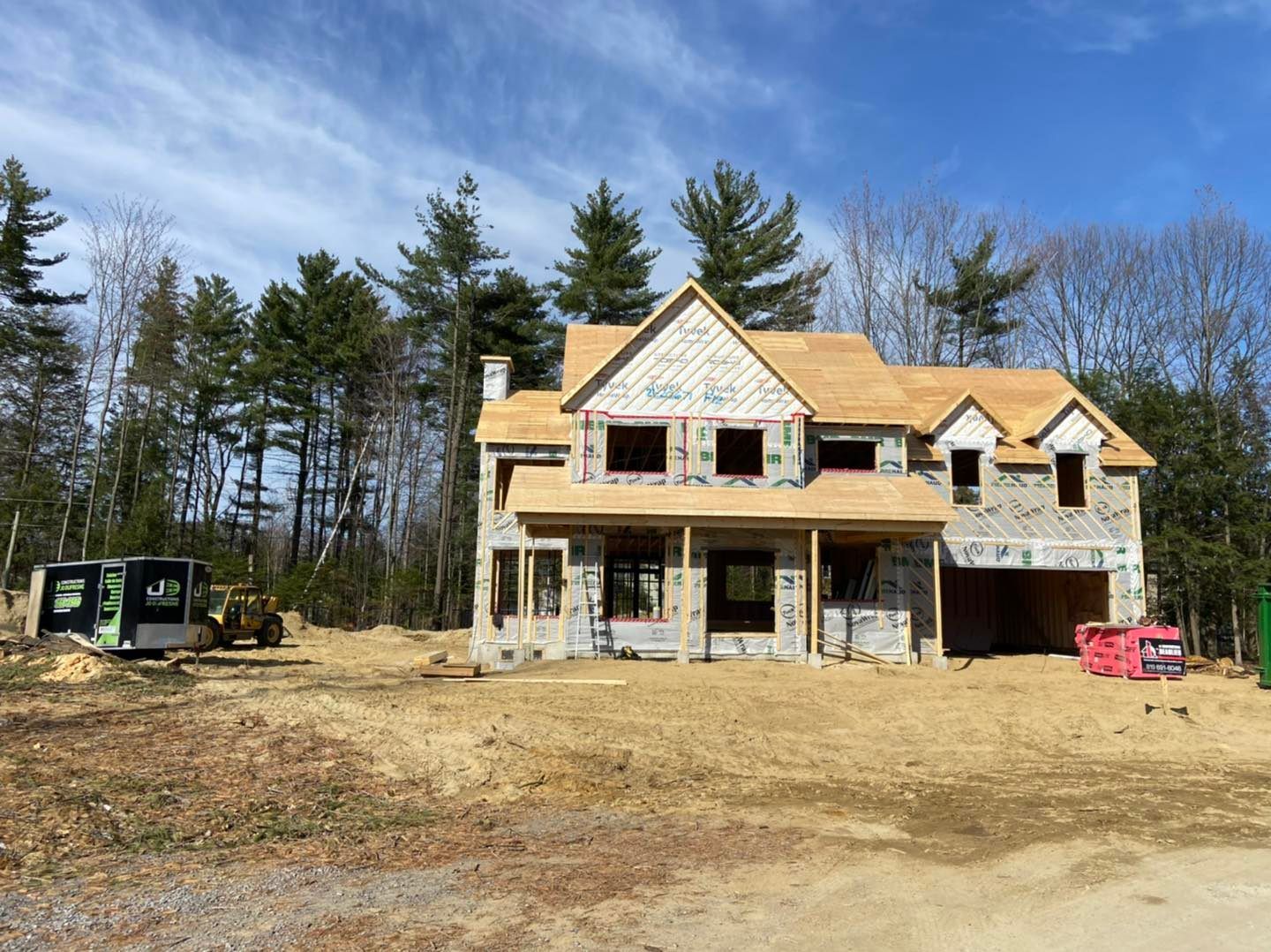 Maison en construction avec charpente et bardage en bois apparents par une journée ensoleillée.
